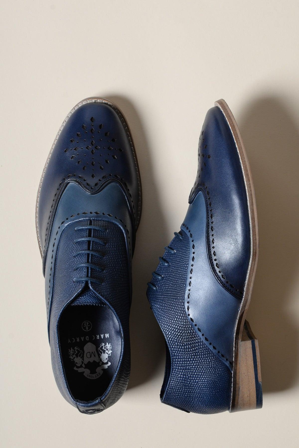 The Marc Darcy RYAN Navy Blue Leather Wingtip Brogue Shoe, shown upright and on its side on a light beige surface, is the perfect formal footwear for any occasion.