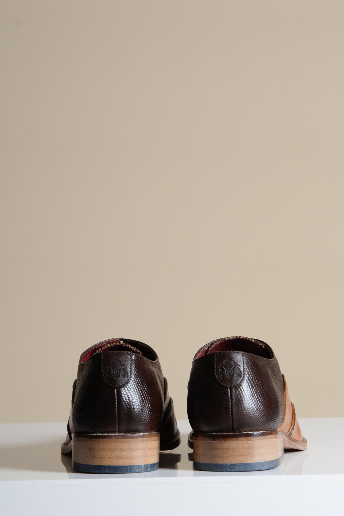 The Marc Darcy RYAN Tan Brown Leather Wingtip Brogue Shoes are displayed from the back on a white surface with a beige background.