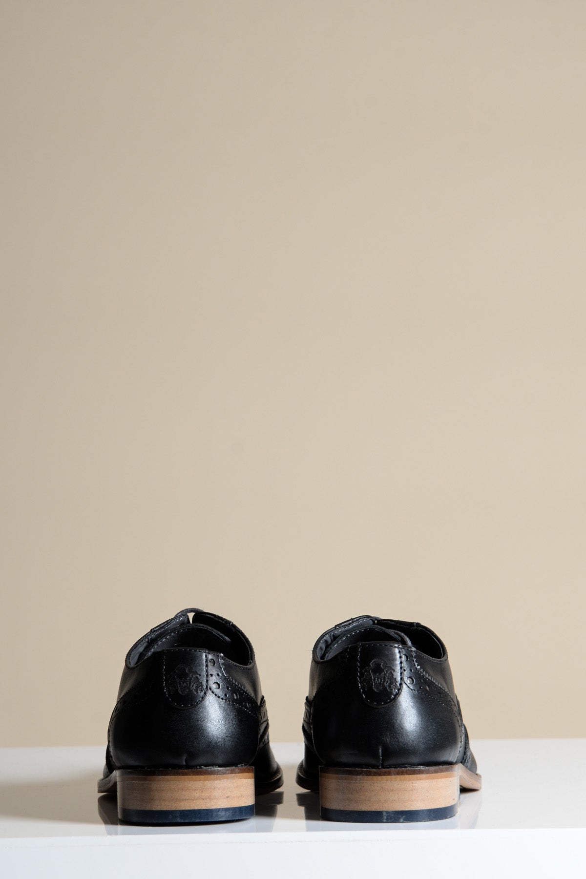 The MARCO Black Grey Leather Wingtip Oxford Shoes by Marc Darcy are shown from the back, placed on a white surface with a plain beige background.