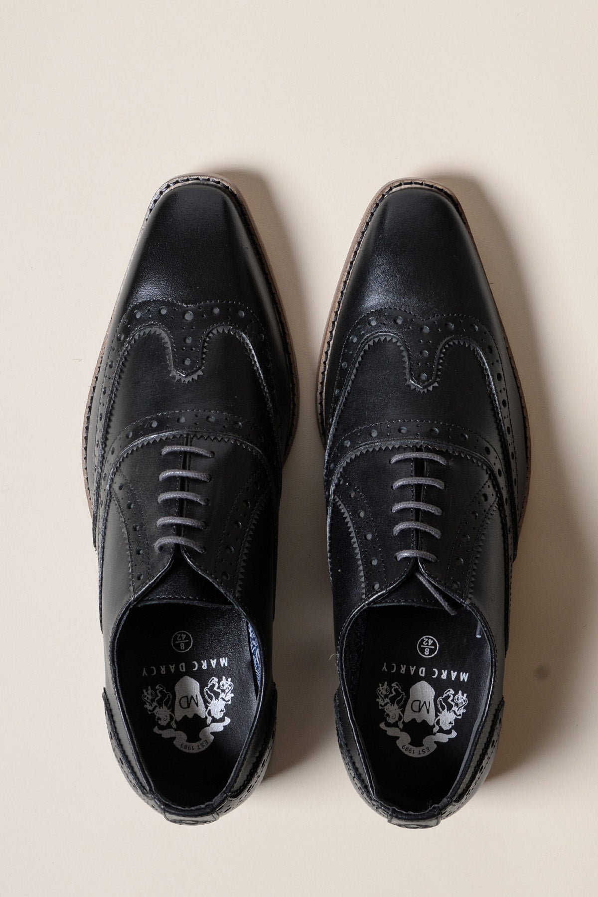 The MARCO Black Grey Leather Wingtip Oxford Shoe by Marc Darcy, crafted from full grain leather with decorative perforations and stitching, is displayed from above on a light beige background.