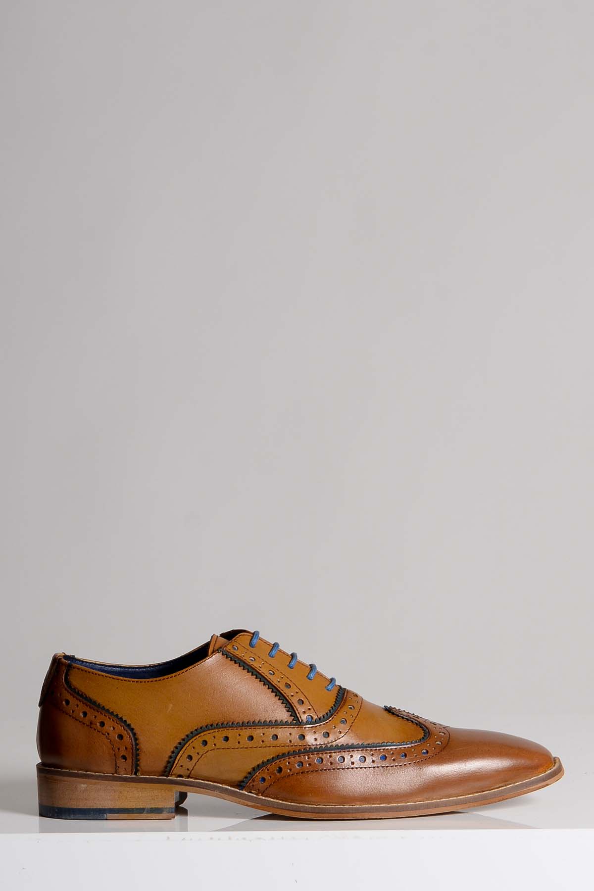 The MARCO - Tan Blue Leather Wingtip Oxford Shoe by Marc Darcy features brogue detailing, blue laces, a low stacked heel, and is crafted from full grain leather, shown against a plain light grey background.