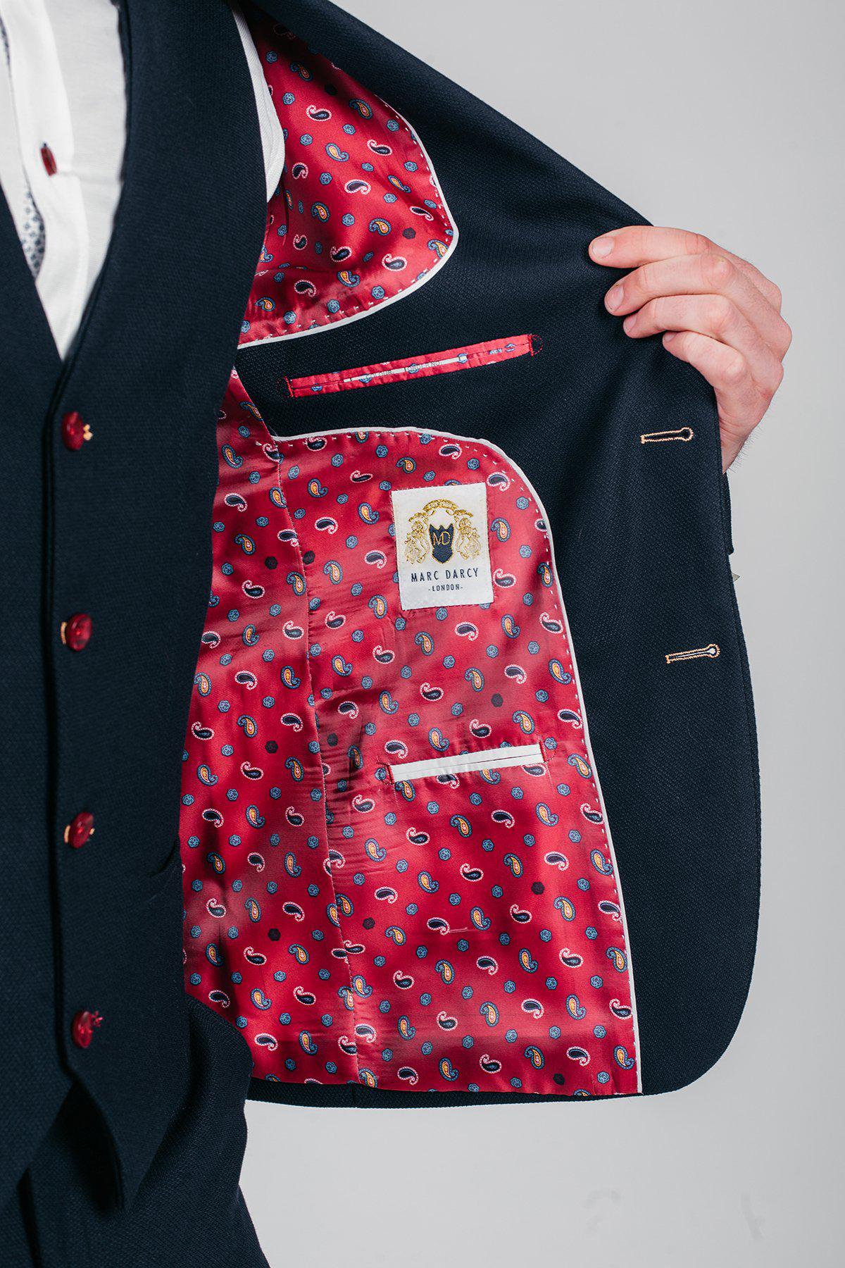 A close-up of the marcdarcy JD4 Navy Suit, as worn by Newcastle United and England goalkeeper Nick Pope, reveals a striking red paisley lining with blue and yellow details—adding flair to this classic men's three-piece ensemble.