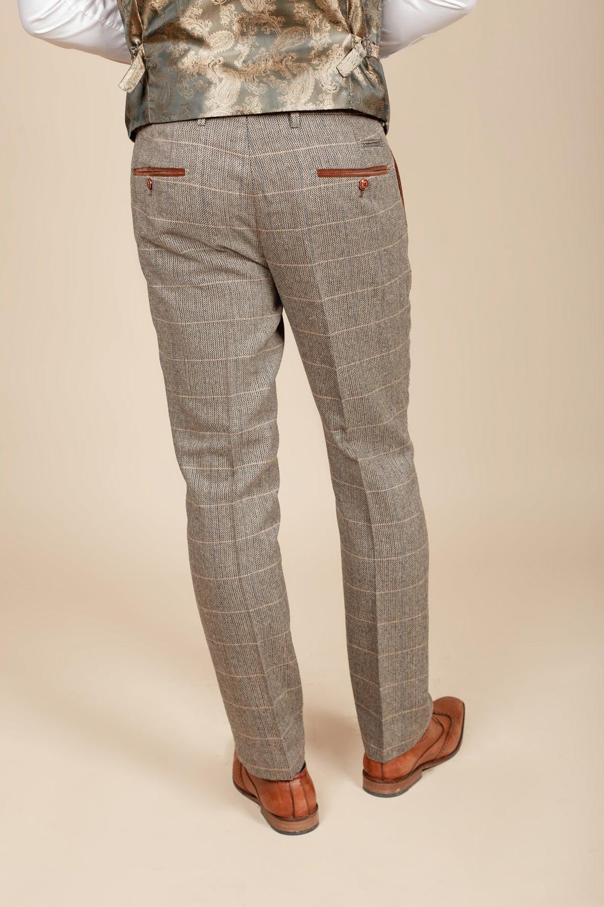 A man wearing marcdarcy's DX7 - Tan Tweed Check Trousers, paired with a paisley vest and brown leather shoes, captured from behind—a Peaky Blinders-inspired vintage style.