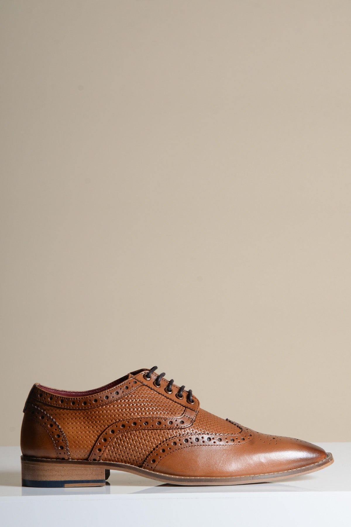 The marcdarcy BRANDON is a dark tan leather wingtip brogue shoe with laces, shown singly on a white surface against a plain beige background.