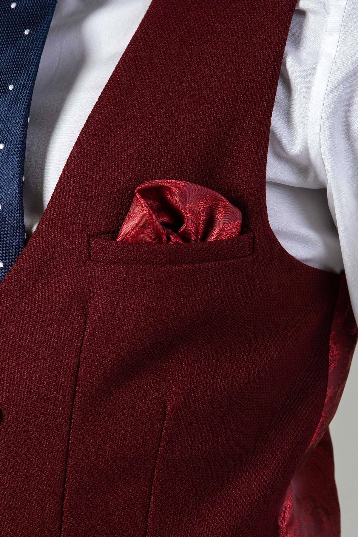 A close-up of a person wearing the marcdarcy KELVIN Wine Double Breasted Waistcoat, paired with a white dress shirt, blue polka dot tie, and a red patterned pocket square neatly placed in the vest pocket.
