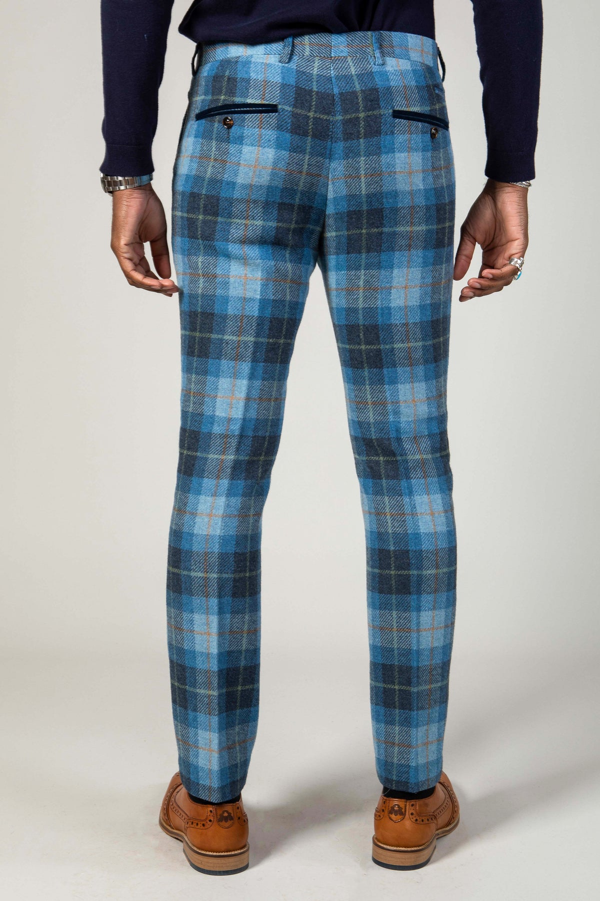 Back view of a man wearing Marc Darcy MORRIS - Blue Tweed Check Trousers with a navy sweater and brown wingtip shoes.