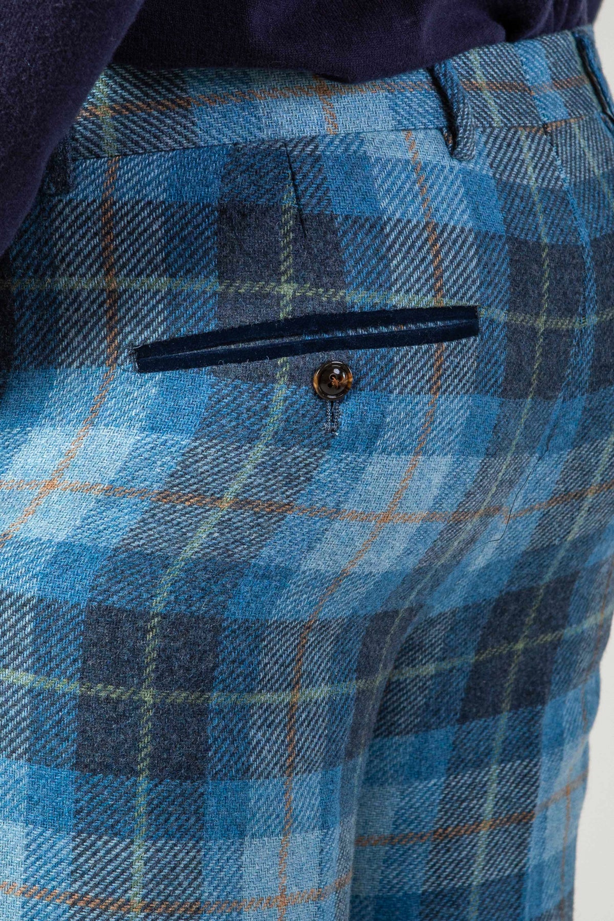 Close-up of a person wearing Marc Darcy’s MORRIS Blue Tweed Check Trousers, featuring a buttoned back pocket, dark waistband, and premium fabric with meticulous stitching.