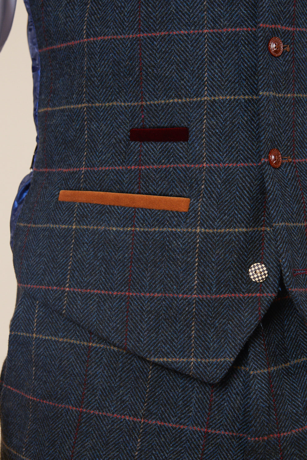 Close-up of the ETON Single Breasted Navy Blue Tweed Check Waistcoat by marcdarcy, showcasing a vintage appeal with its blue checkered pattern, red and orange pocket trim, multiple buttons, and side blue lining.
