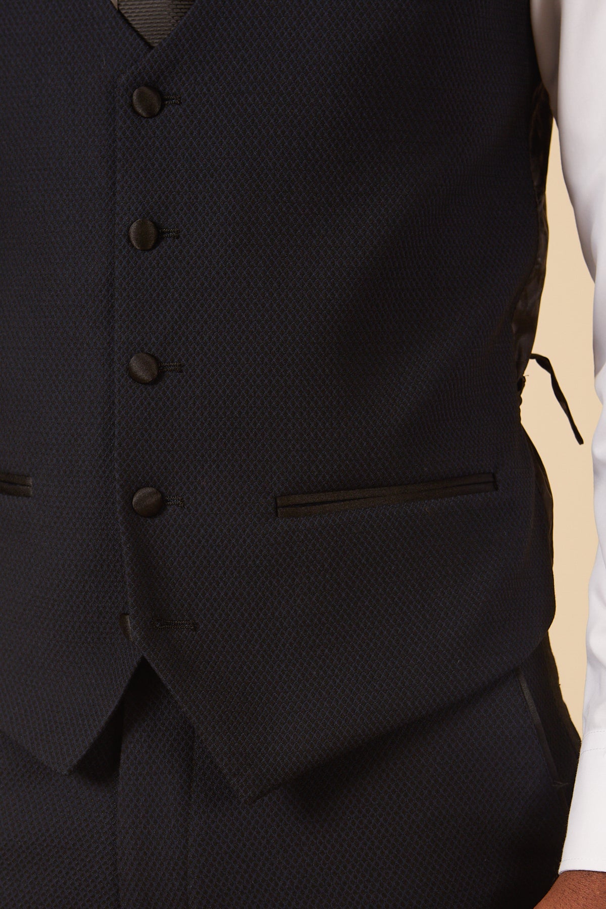 A close-up of the DALTON Navy Tux Lapel Diamond Three Piece Suit by marcdarcy, showcasing its dark blue patterned vest with four dark buttons and a subtle pocket detail.