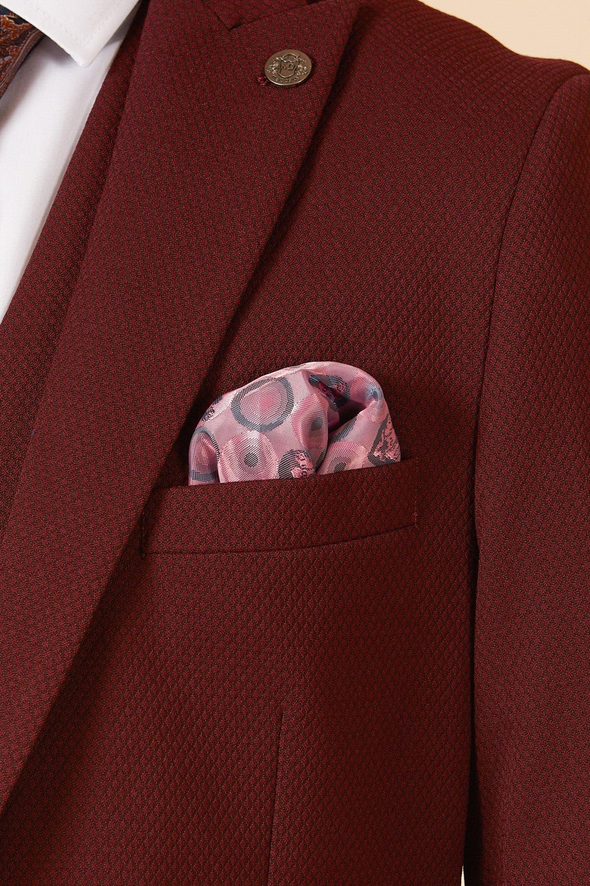 The marcdarcy MAX Wine Three Piece Suit features a blazer, white shirt, patterned tie, lapel pin, and pink floral pocket square—perfect for a stylish wedding guest ensemble.