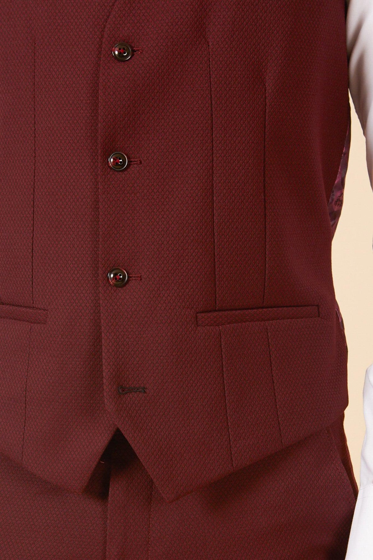 Close-up of a dark red, textured vest with three buttons and welt pocket from the marcdarcy MAX - Wine Three Piece Suit—ideal for elevating your formal look or as a stylish wedding guest option.
