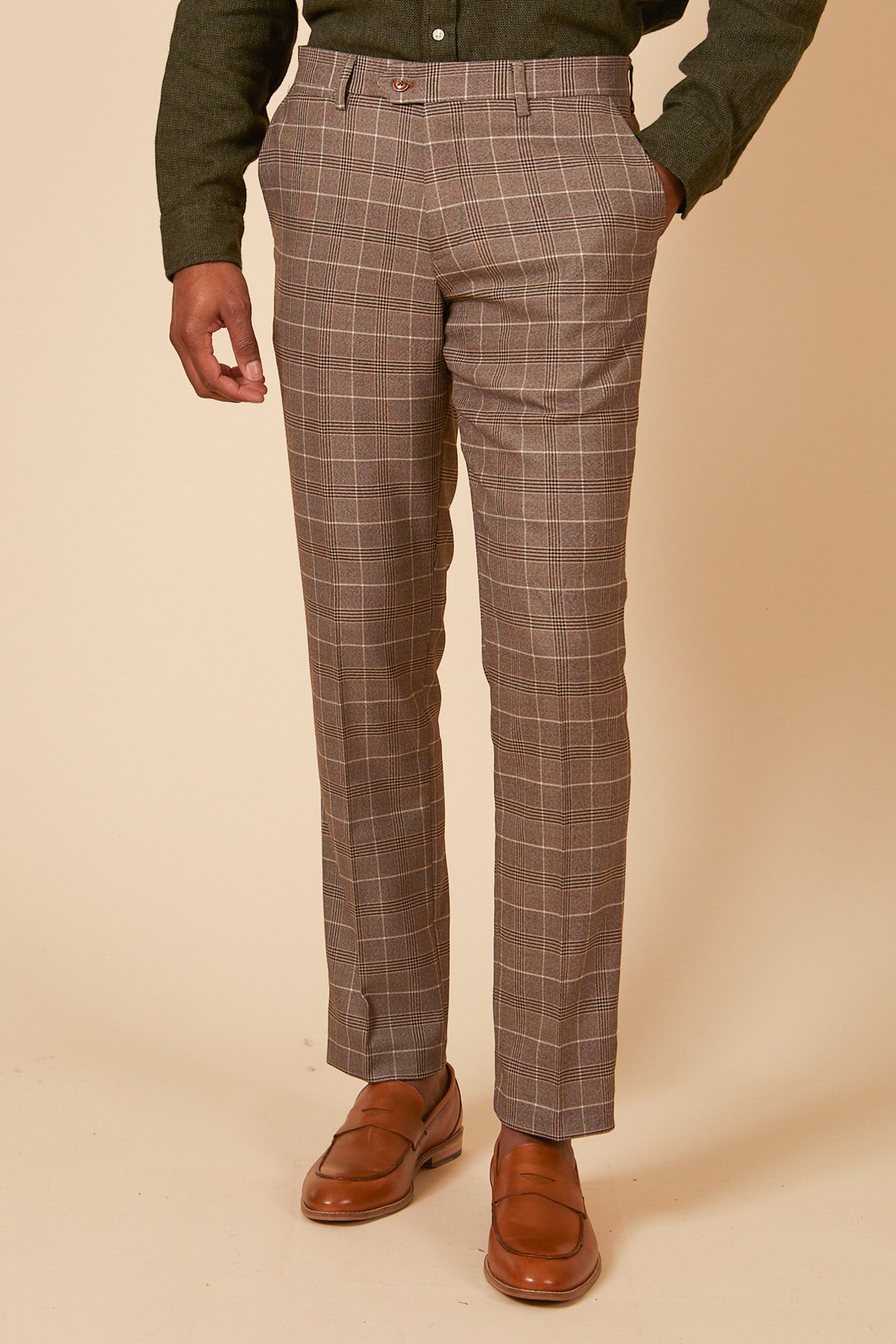 A person wearing the marcdarcy RAY Tan Check Three Piece Suit stands with one hand in their pocket against a beige background—perfect for stylish office wear.