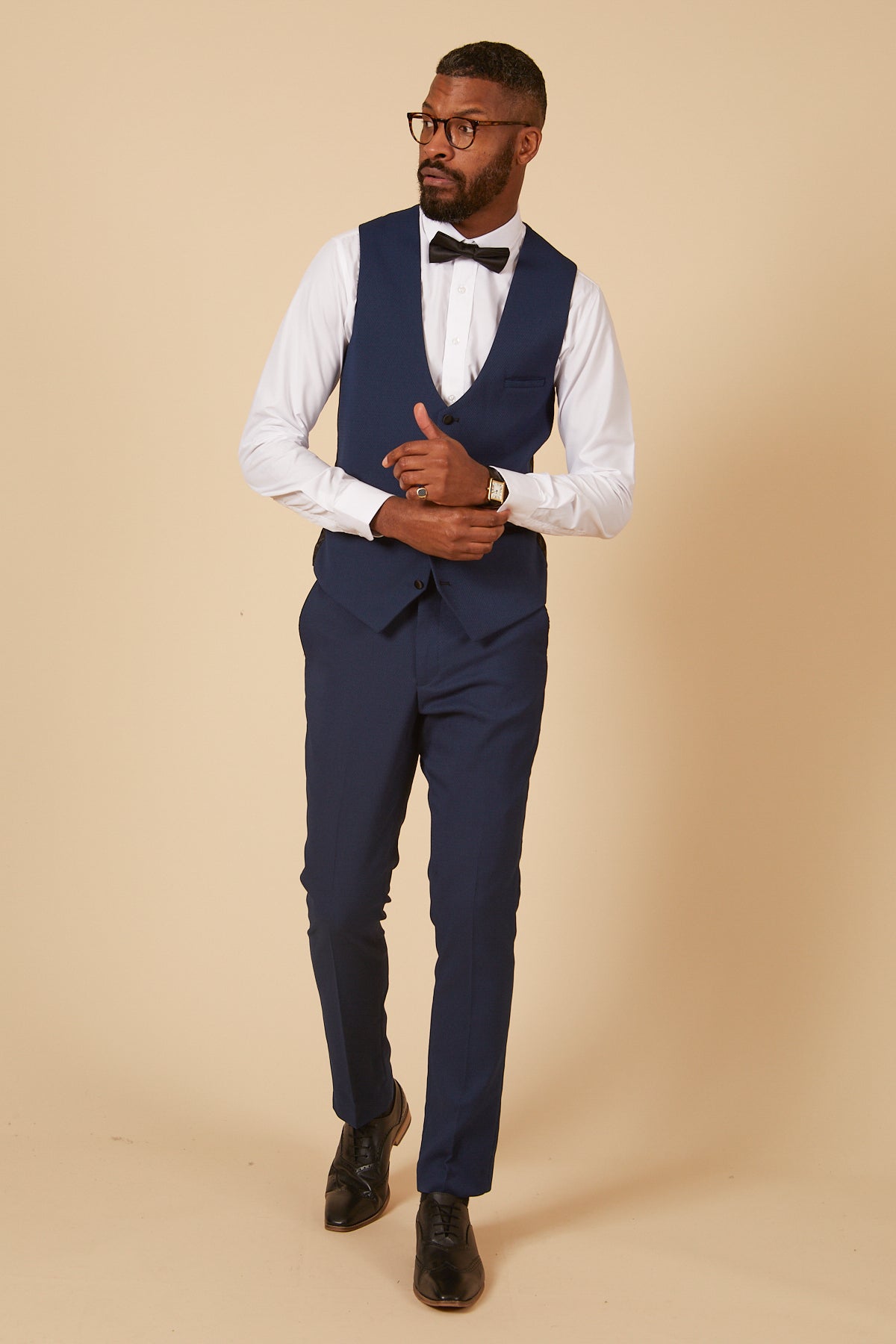 Charlie Wrenshall as Liam Connor wears the marcdarcy DALTON Royal Blue Tux Suit with peak lapel, white shirt, and black bow tie, posing confidently with crossed hands and glasses.