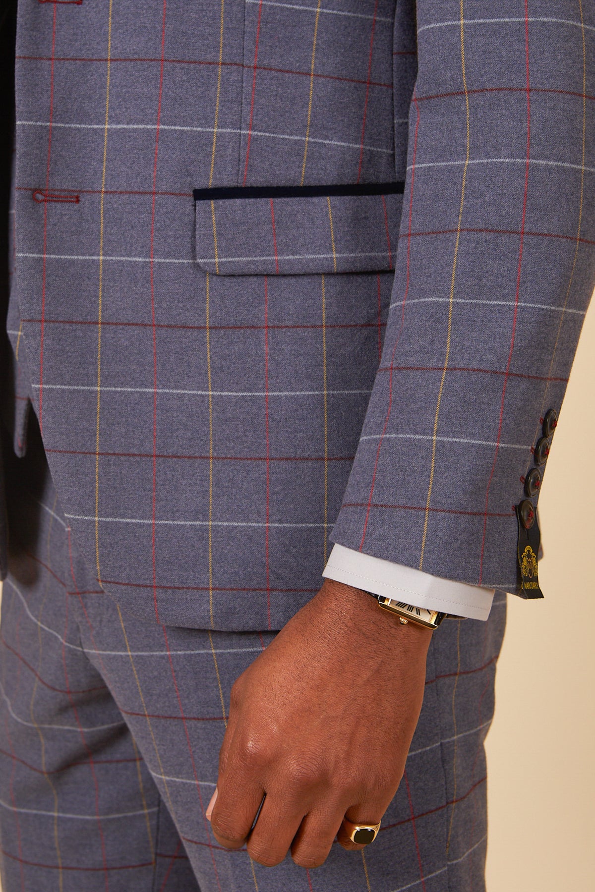 A close-up of a person wearing the marcdarcy DRAKE - Sky Blue Check Three Piece Suit, showing their hand with a gold ring and watch, plus detailed views of the suit's pocket and sleeve buttons.