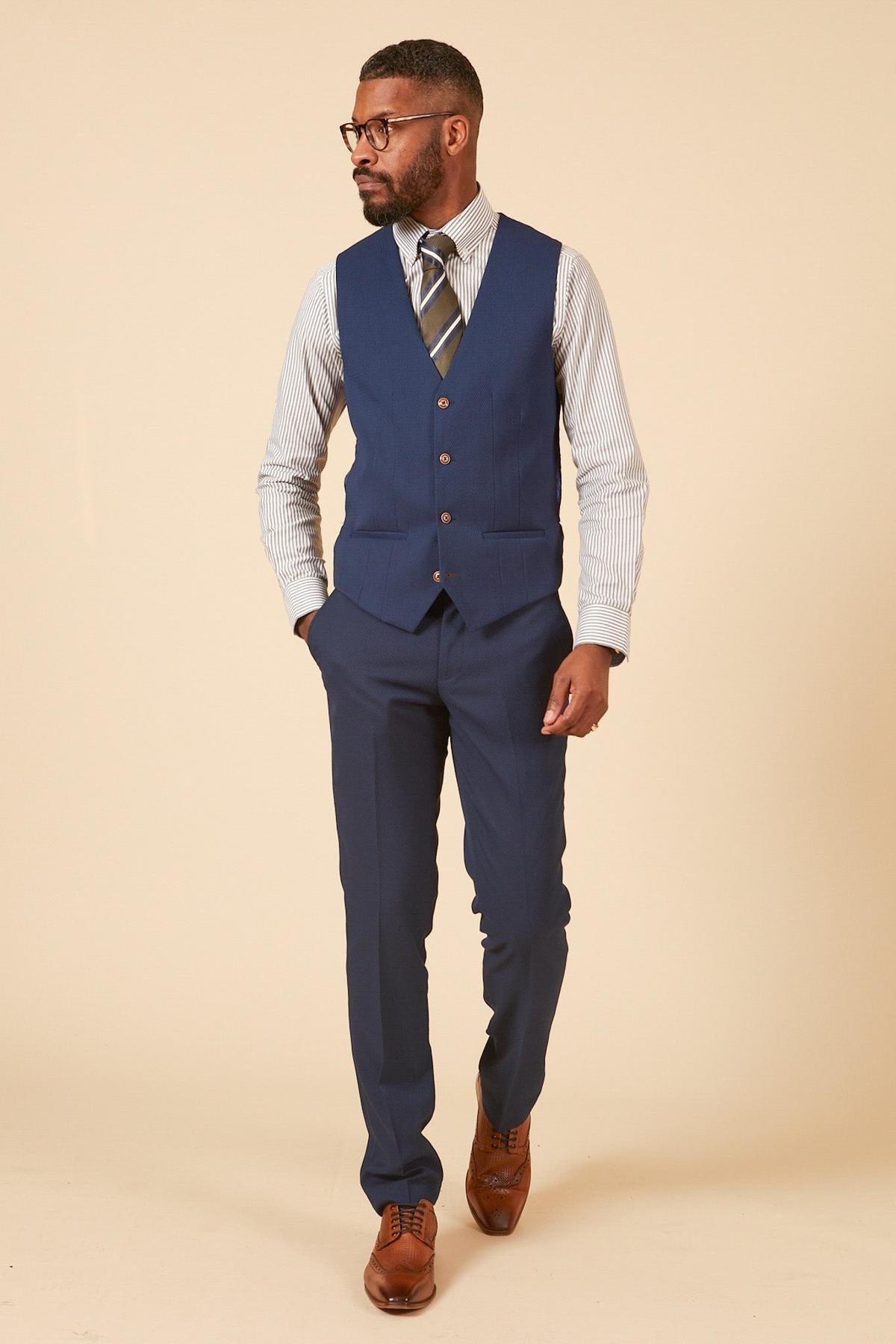 Man in a slim fit marcdarcy MAX Royal Blue Single Breasted Waistcoat, striped shirt, pants, brown shoes, and glasses—ideal for sharp office wear.