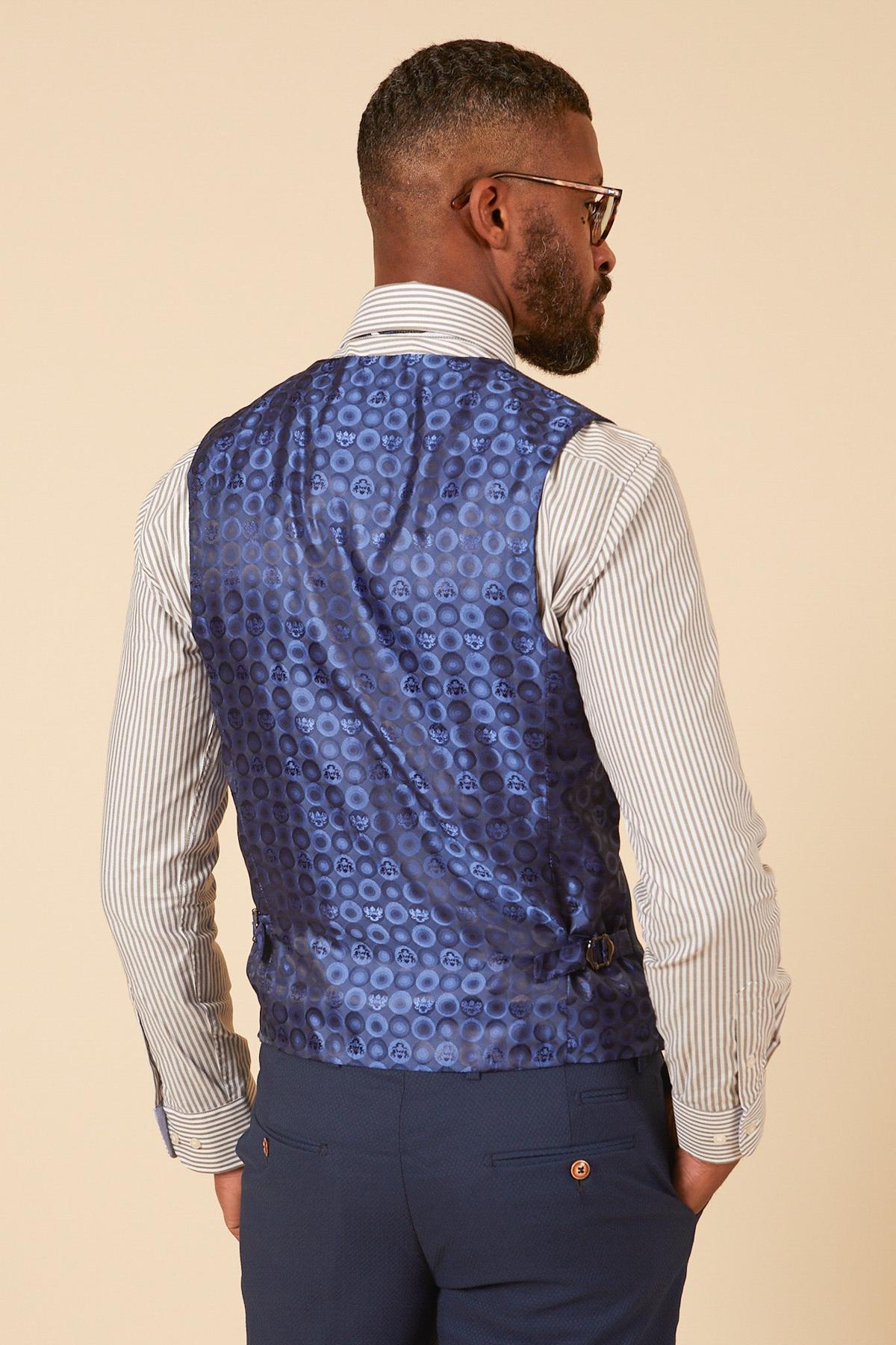 Back view of a man in marcdarcy's MAX Royal Blue Single Breasted Waistcoat with circle print lining, white striped shirt, and navy trousers—ideal for smart office wear. He has a beard, glasses, and hands in pockets.