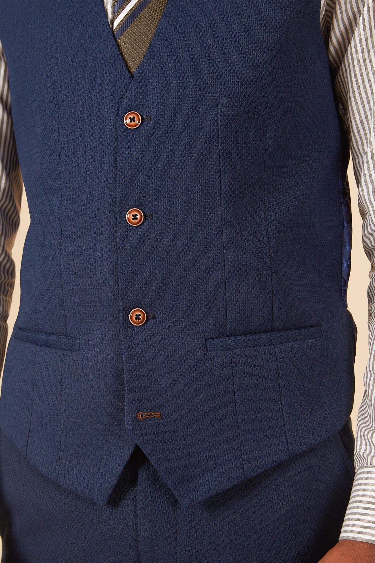 A close-up of a person wearing the marcdarcy MAX Royal Blue Single Breasted Waistcoat with brown buttons, two front pockets, over a striped shirt and matching trousers, styled with a striped tie for a polished office look.