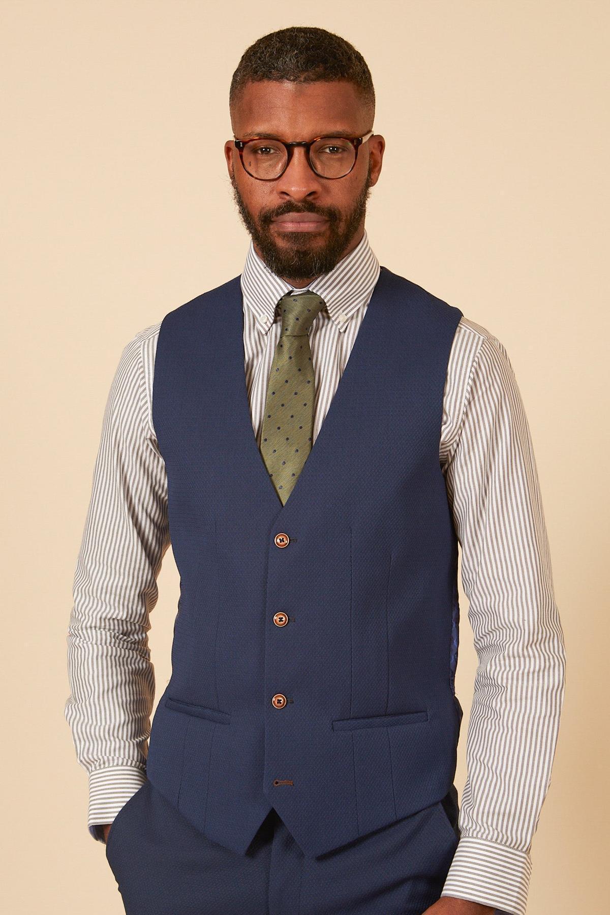 Man with beard and glasses wearing a marcdarcy MAX Royal Blue Single Breasted Waistcoat over a striped shirt and green tie, ideal for smart office wear.