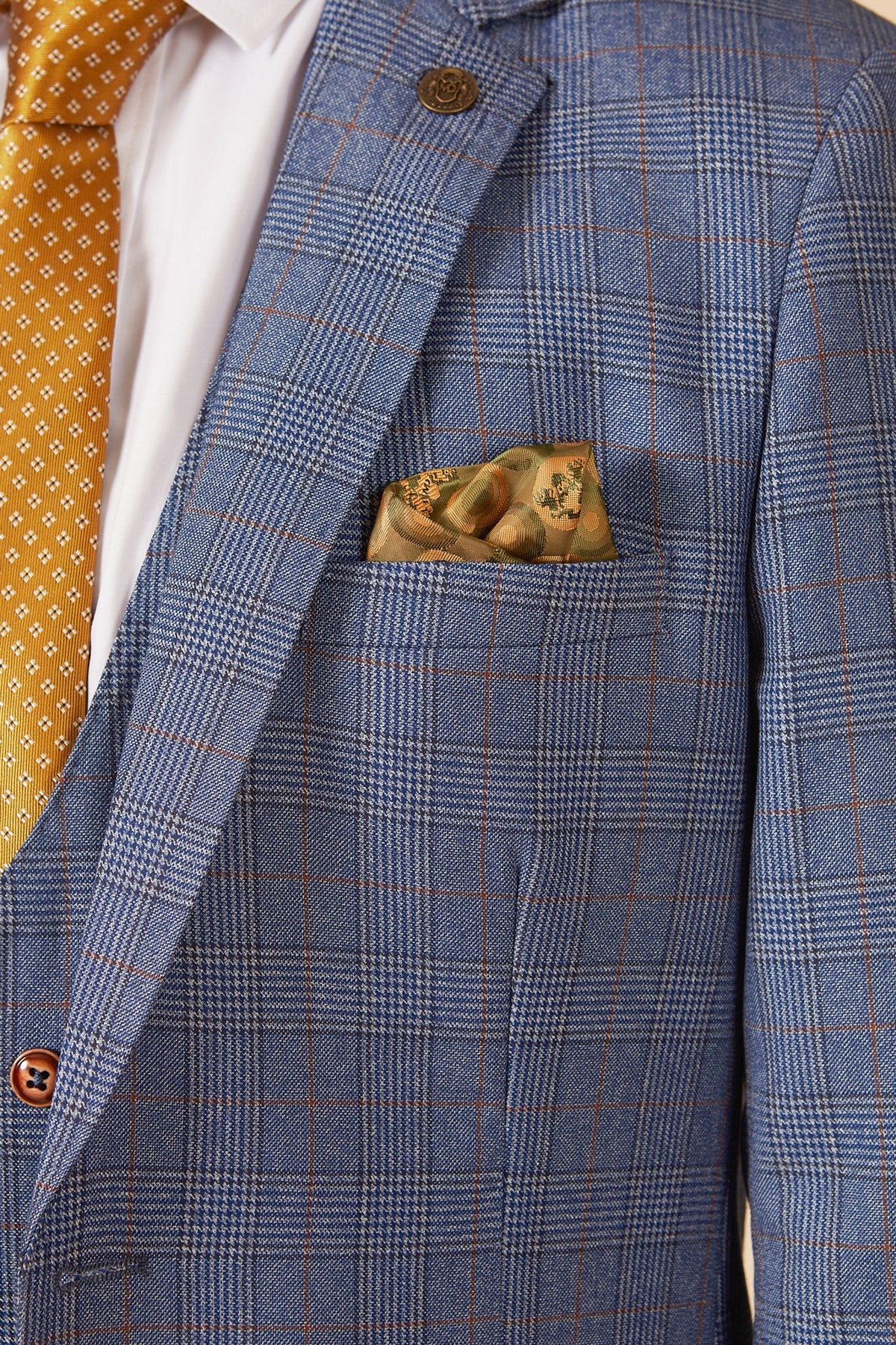 A person wearing the marcdarcy GEORGE light blue check three piece suit with a brown and gold patterned pocket square, white dress shirt, and a yellow tie with small white designs.
