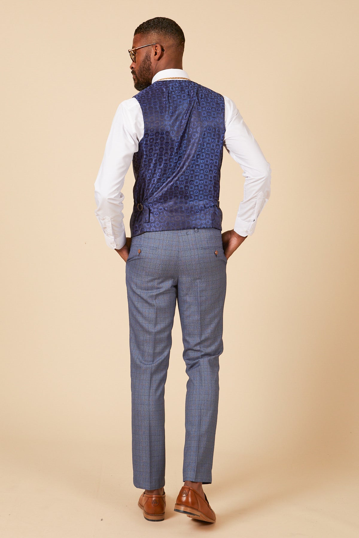 A man stands with his back to the camera, wearing the marcdarcy GEORGE Light Blue Check Three Piece Suit against a beige background.