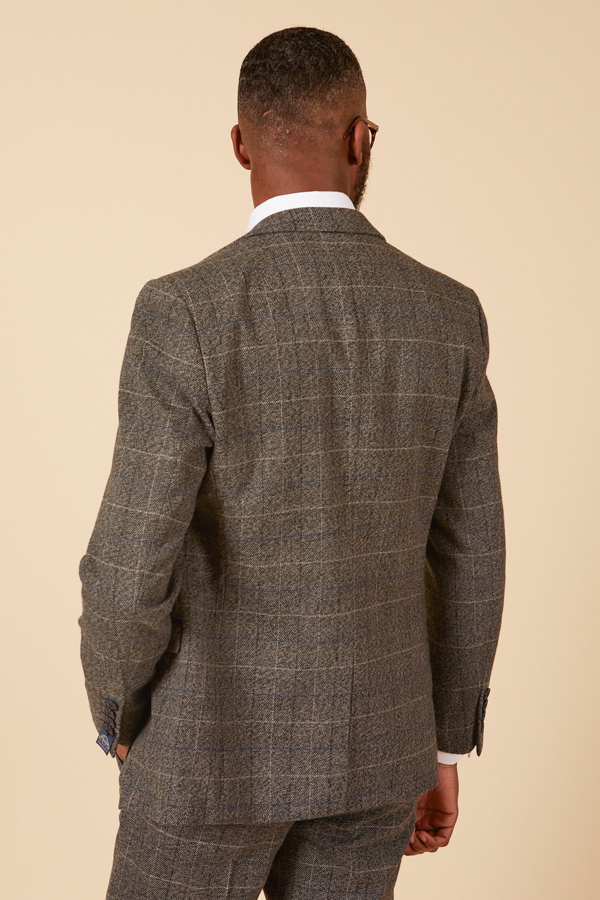 A man wearing the marcdarcy SCOTT Grey Tweed Check Blazer with a white dress shirt stands with his back to the camera against a beige background.