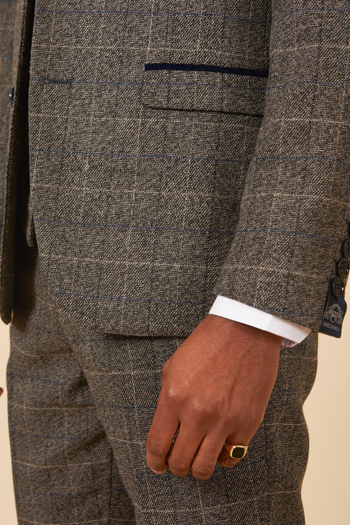 A close-up of the lower torso, arm, and hand shows a person in the marcdarcy SCOTT - Grey Tweed Check Blazer with navy velvet trims, a white shirt cuff visible, and a gold ring on their right hand.