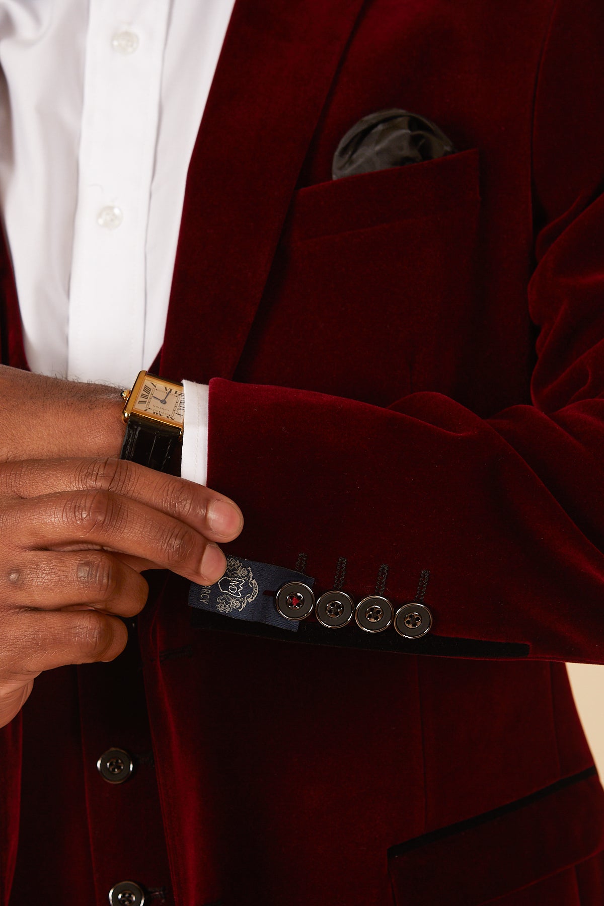 Close up of a man adjusting the tag on the cuff of the marcdarcy HUDSON Wine Velvet Blazer, paired with a white shirt and gold watch.