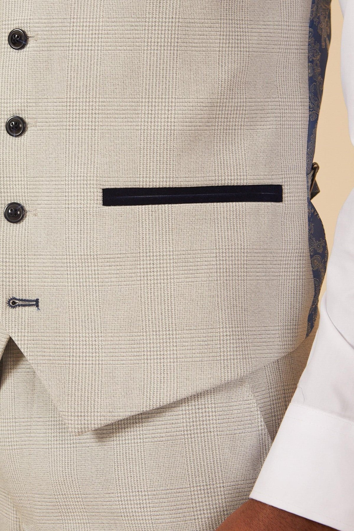 Close-up of former Manchester City footballer Fabian Delph in the Marc Darcy BROMLEY Stone Check Suit, showing the light beige vest with glen plaid pattern, dark buttons, navy pocket trim, and a peek of the patterned lining.