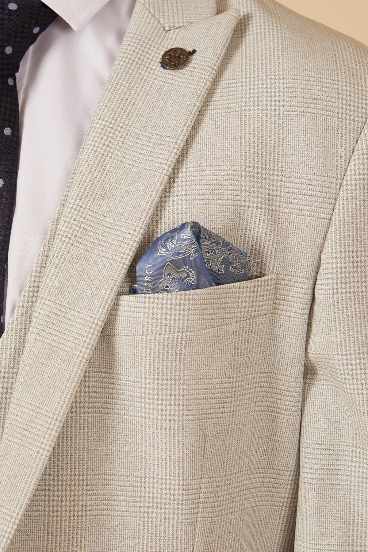 Close-up of former Manchester City footballer Fabian Delph in the BROMLEY Stone Check Suit by Marc Darcy, styled with a white shirt, dark polka dot tie, blue pocket square, and decorative lapel pin.