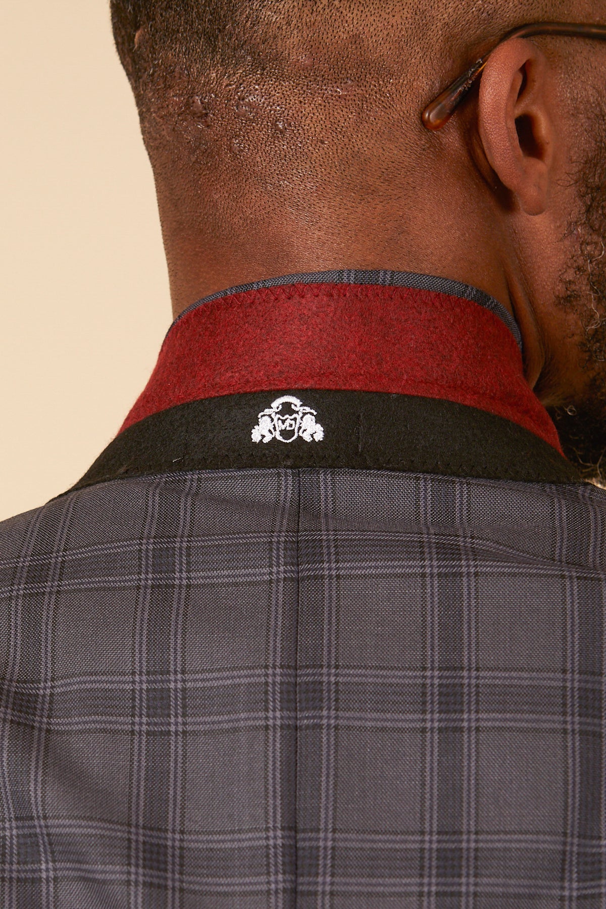 Close-up of the back of a mans neck and shoulders wearing the marcdarcy JOSE Grey Check Three Piece Suit, featuring a red and black collar with a small white embroidered logo near the collar.