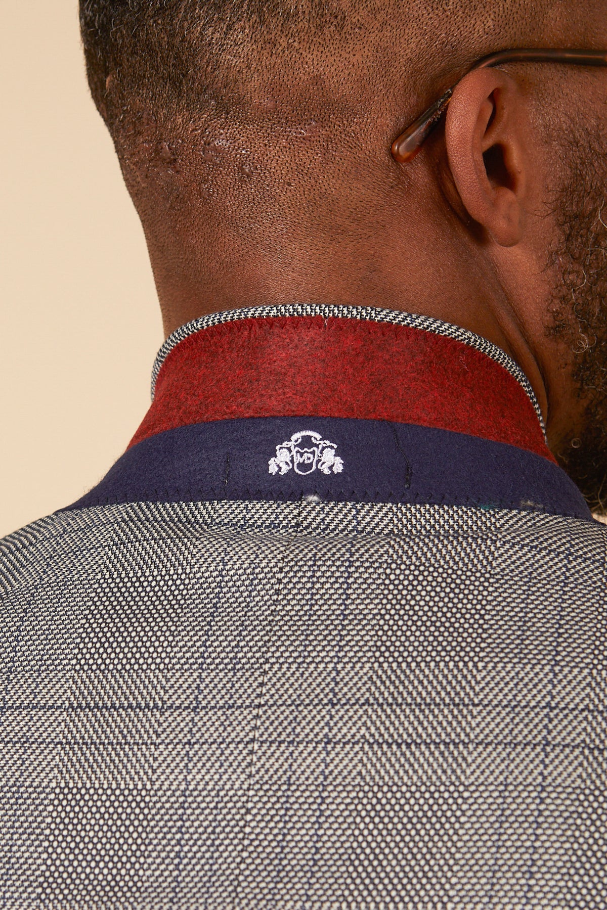Close-up of the back of a man's head and neck wearing the marcdarcy JERRY Grey Check Blazer, featuring a red and navy collar with an embroidered crest.
