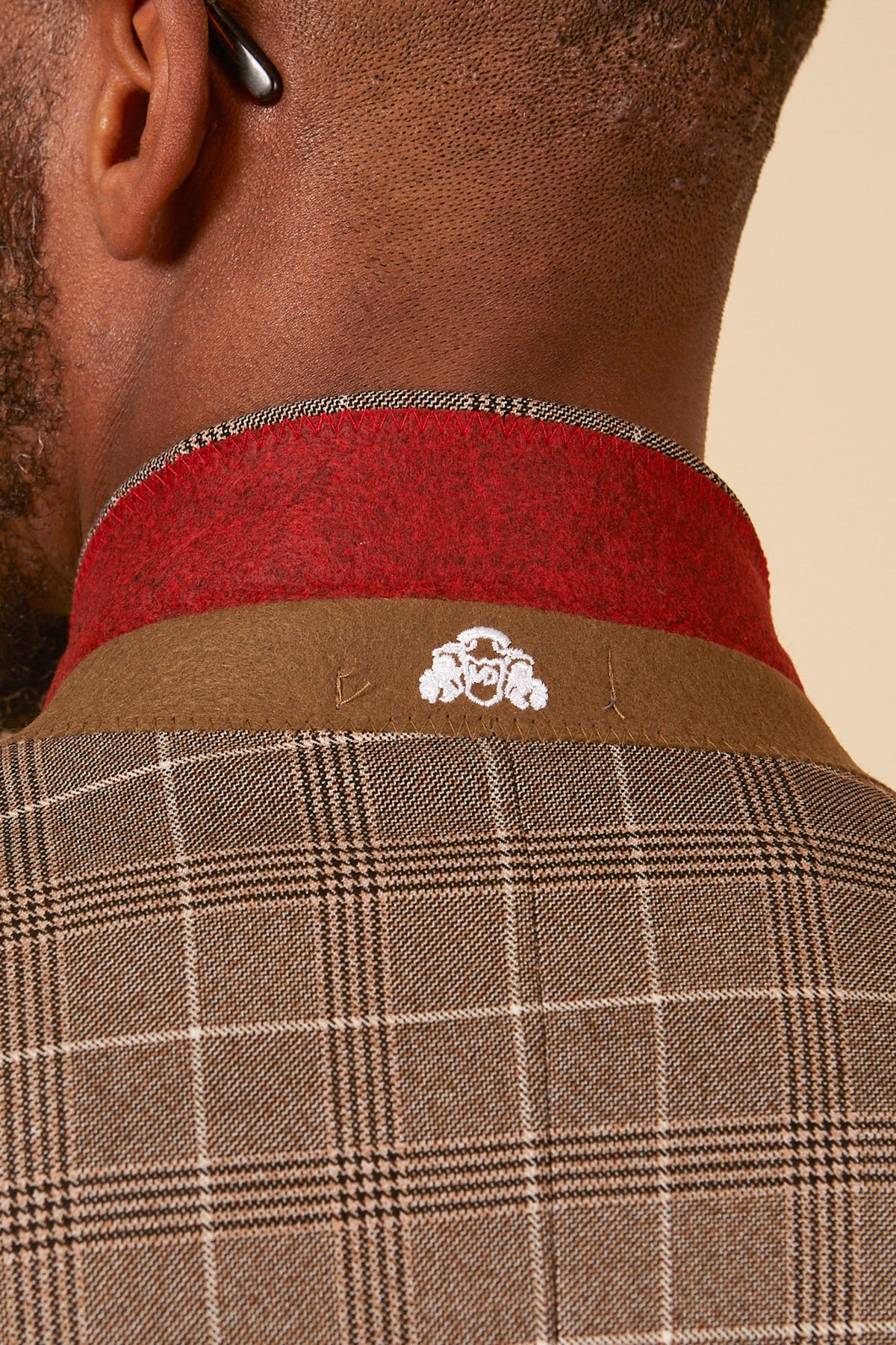 Close-up of the back of a person wearing the marcdarcy RAY - Tan Check Three Piece Suit, featuring a brown and red collar with a small white embroidered detail—an ideal choice for stylish office wear.