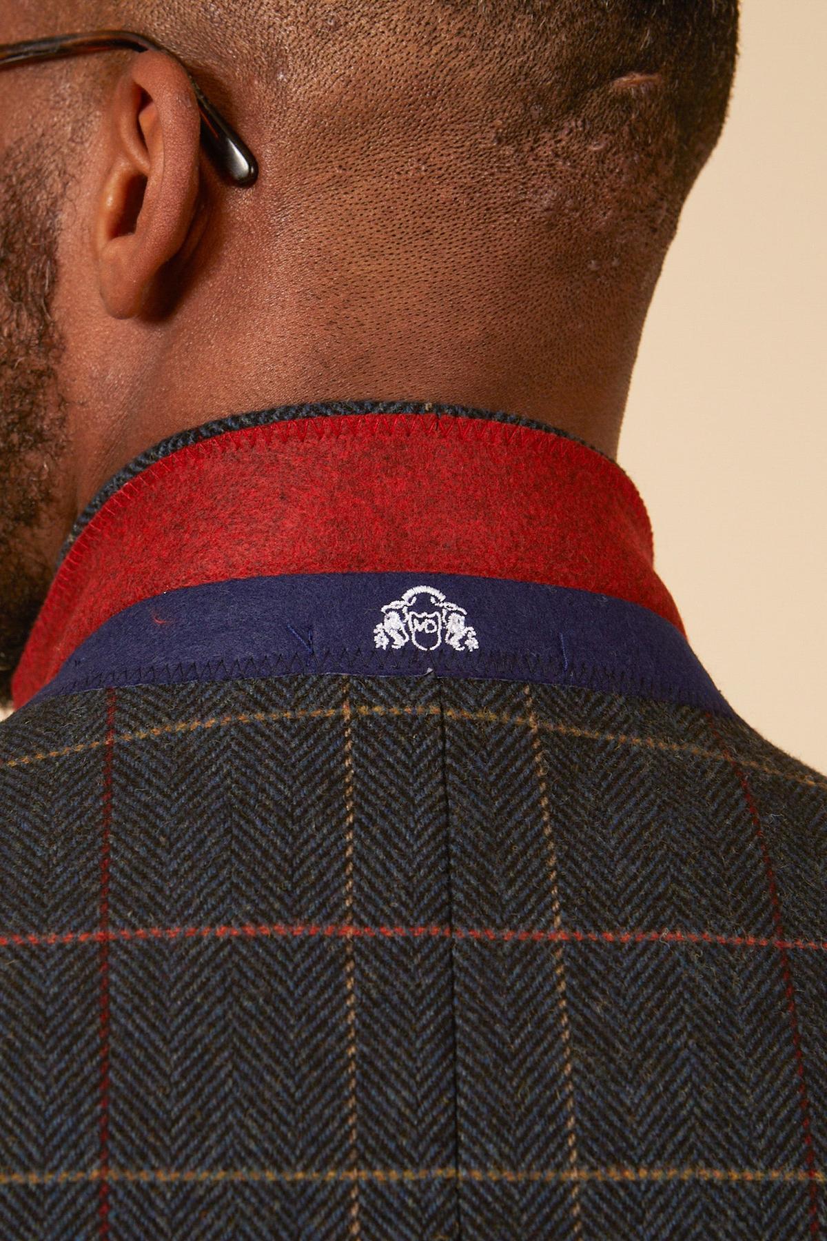 Close-up of the back of a mans neck in the marcdarcy ETON - Navy Blue Tweed Check Blazer, featuring a red collar, blue trim, and a small white embroidered crest below the collar for a smart casual look.