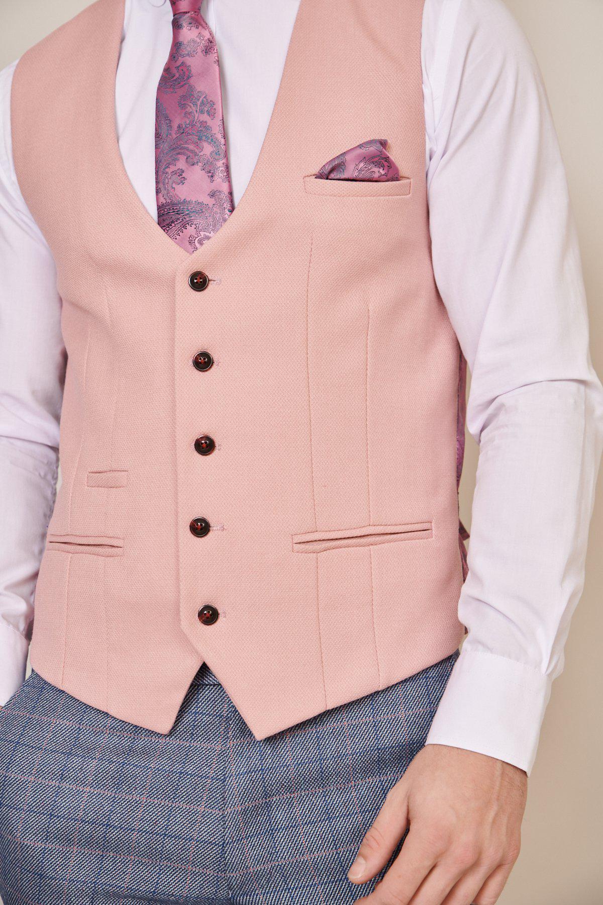 A person wears the marcdarcy KELVIN - Pink Single Breasted Waistcoat with black buttons, bespoke MD print lining, matching paisley tie and pocket square, a white dress shirt, and blue plaid trousers—a formal and stylish look.
