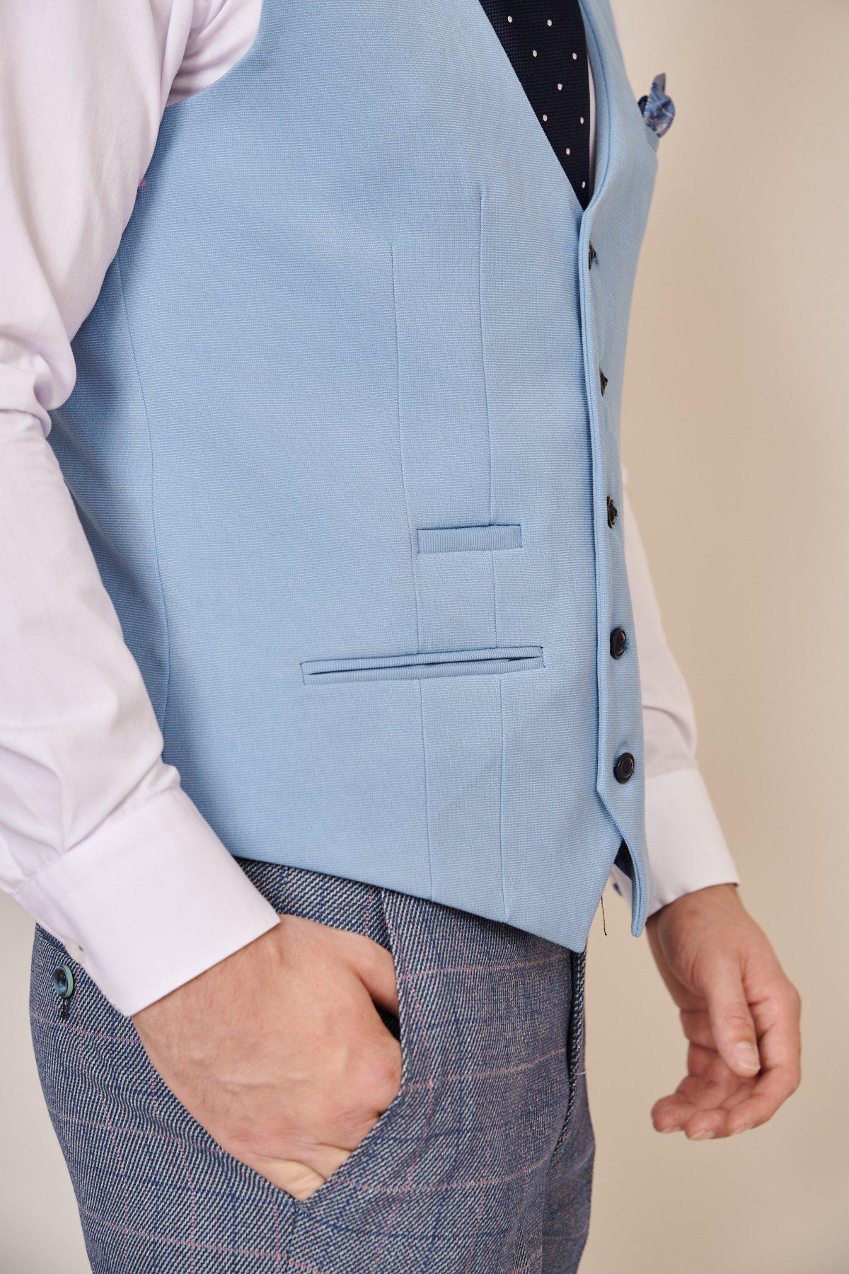 A person wears the marcdarcy KELLY Sky Blue Single Breasted Waistcoat over a white shirt, paired with a black polka dot tie and gray plaid trousers; this slim fit waistcoat adds a modern twist to the classic look.