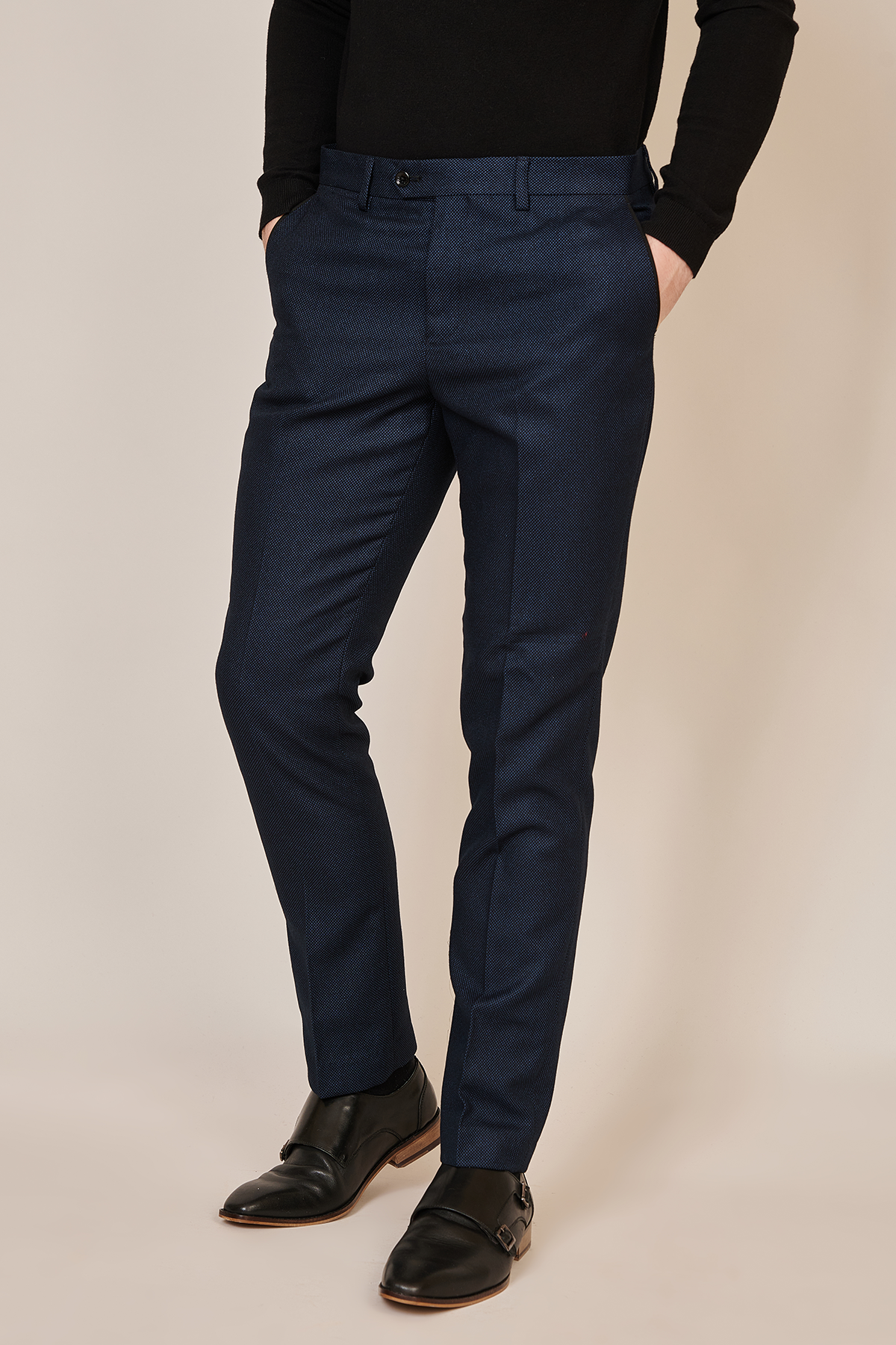 A person stands with hands in pockets against a light background, wearing marcdarcys CALLUM Navy Blue Trouser, a black long-sleeve shirt, and black dress shoes for a polished formal look.
