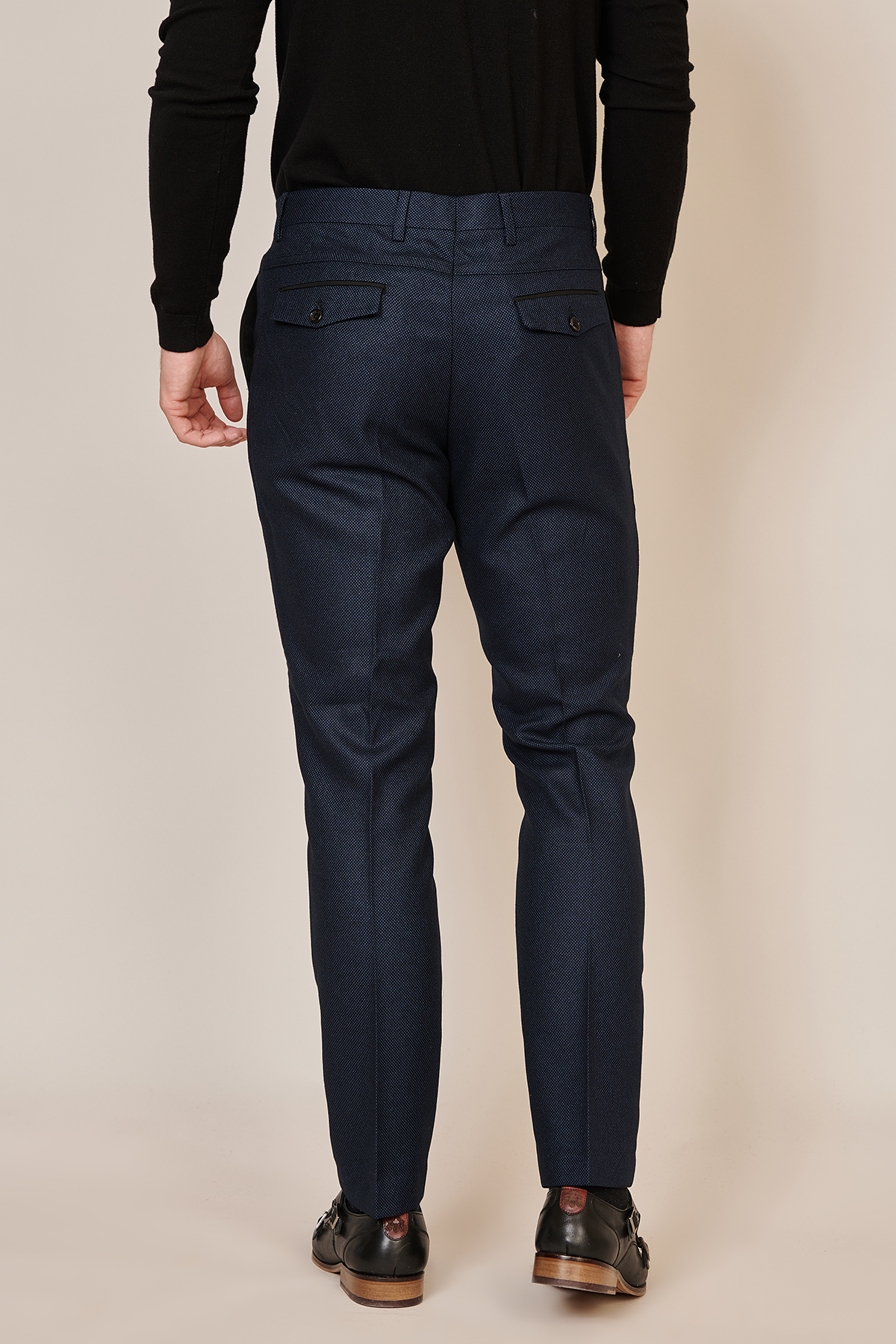A man is seen from the back wearing marcdarcy's CALLUM Navy Blue Trouser with a tailored fit and buttoned-flap back pockets, paired with a black long-sleeve shirt and black dress shoes.