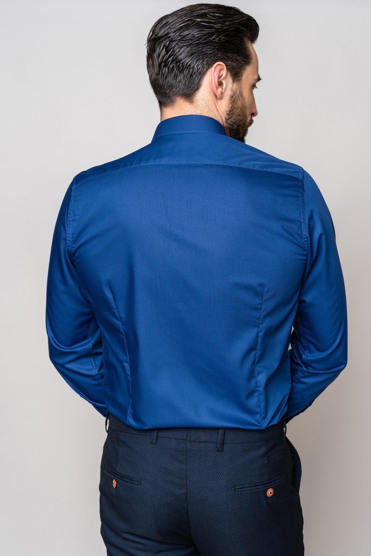 A man with dark hair, wearing a Marc Darcy CARTER Navy Long Sleeve Shirt in a classic fit and dark pants, stands with his back to the camera against a light-colored background.
