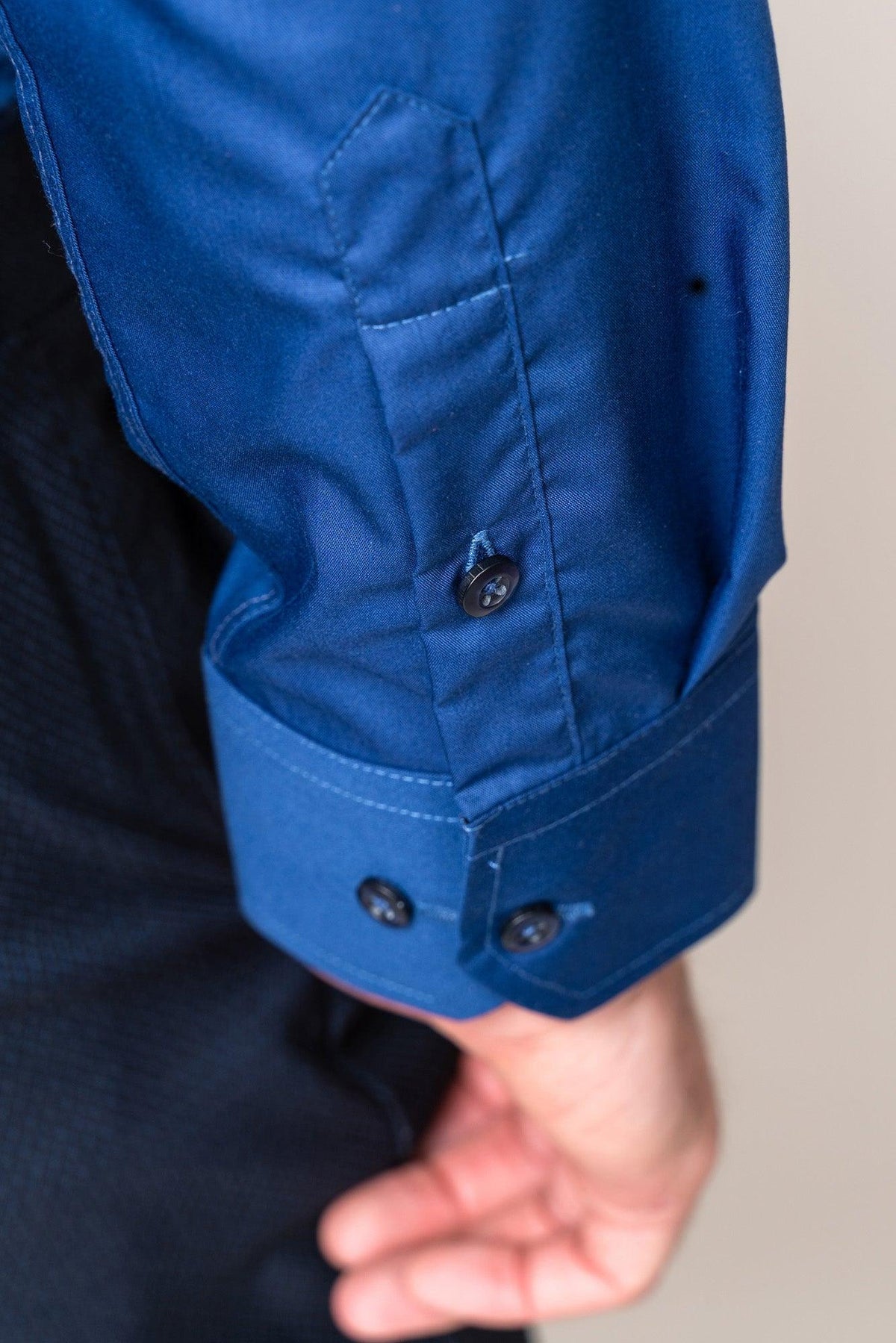 A close-up of a person’s arm in the Marc Darcy CARTER - Navy Long Sleeve Shirt with dark cuff buttons. The neatly stitched, slightly bent sleeve showcases its classic fit style.