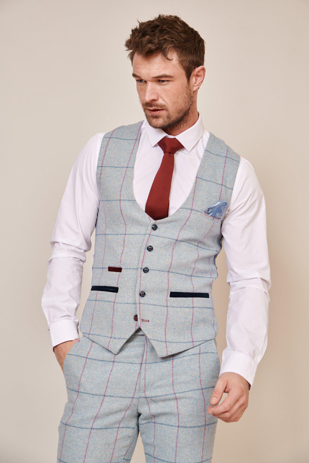 Wearing the Marc Darcy NICOLAS - Sky Tweed Check Waistcoat with coordinating pants, white shirt, red tie, and sky blue check pocket square, a man stands against a plain background—a sharp modern groom’s suit choice.