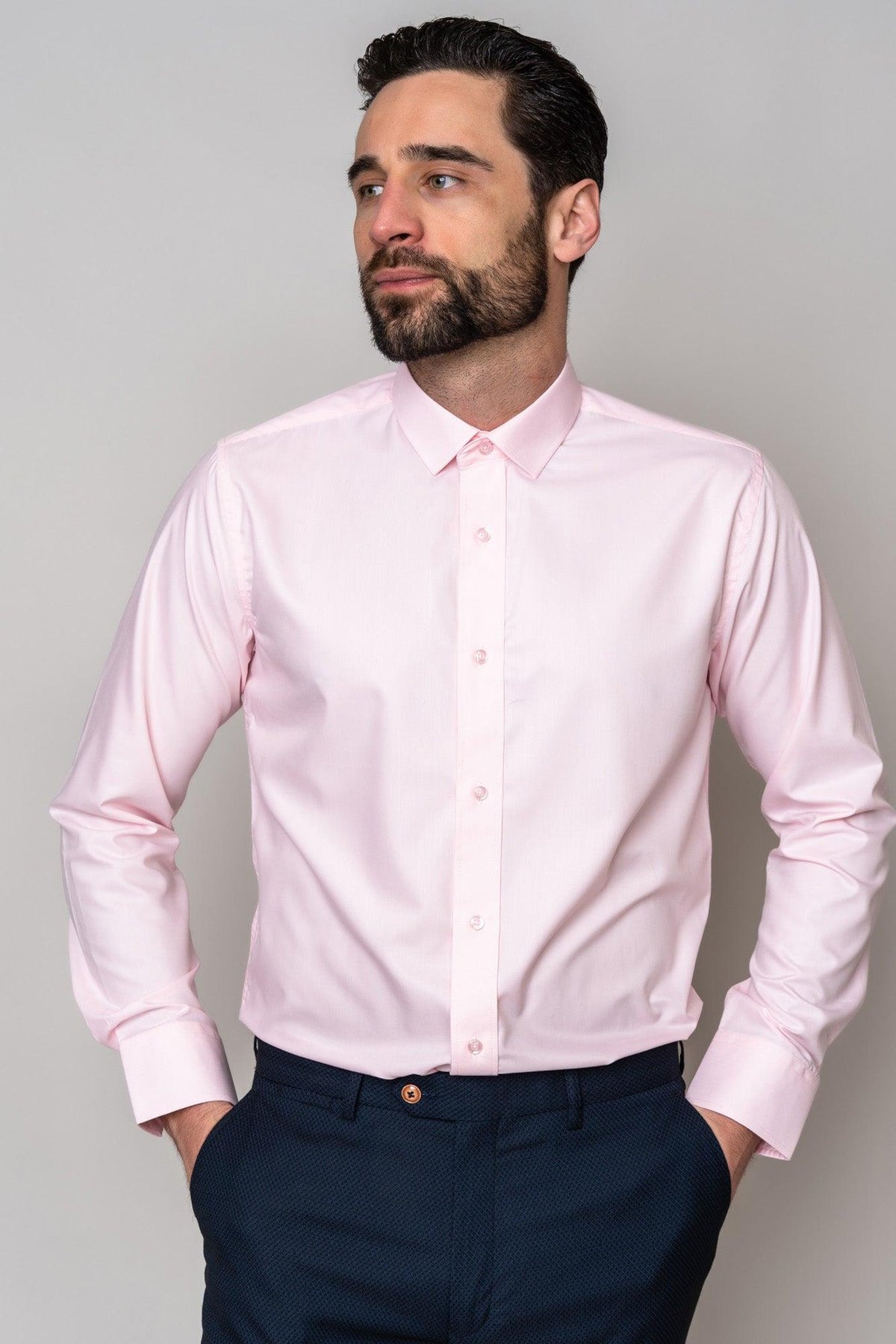 Man wearing the Marc Darcy CARTER Pink Long Sleeve Shirt and dark patterned pants with hands in pockets, highlighting this classic fit shirt—an ideal choice for formalwear.