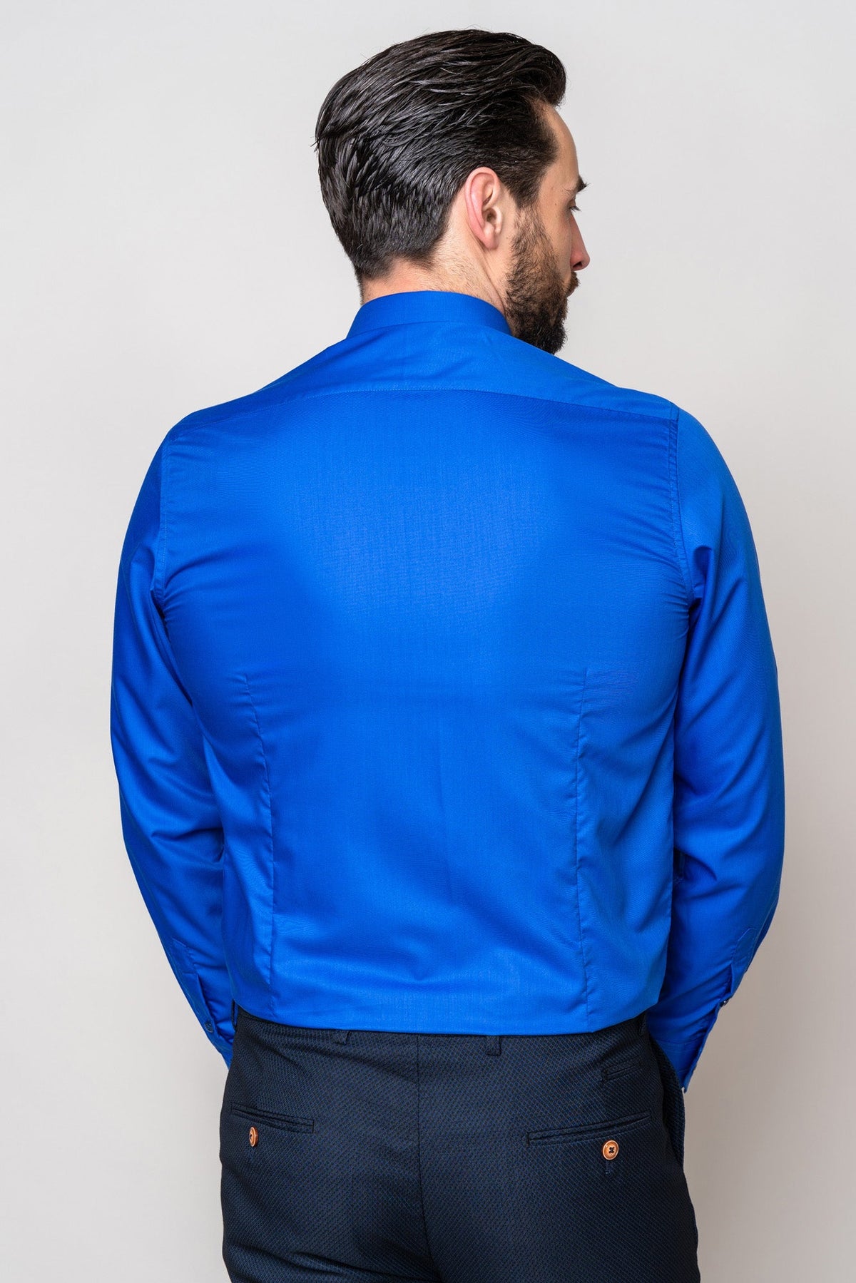 A man with dark hair is shown from the back wearing the CARTER - Royal Long Sleeve Shirt by Marc Darcy and dark pants against a plain light background.