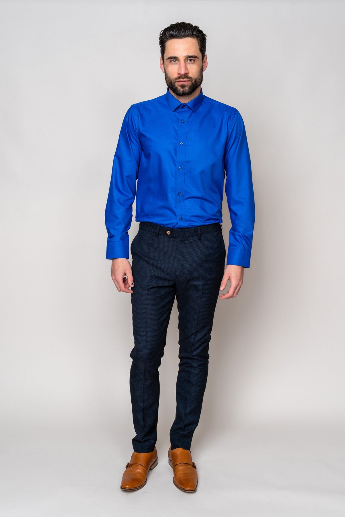 A man with a beard and short hair stands against a plain background wearing the CARTER - Royal Long Sleeve Shirt by Marc Darcy, paired with dark slim-fit trousers and tan dress shoes, facing forward with a neutral expression.