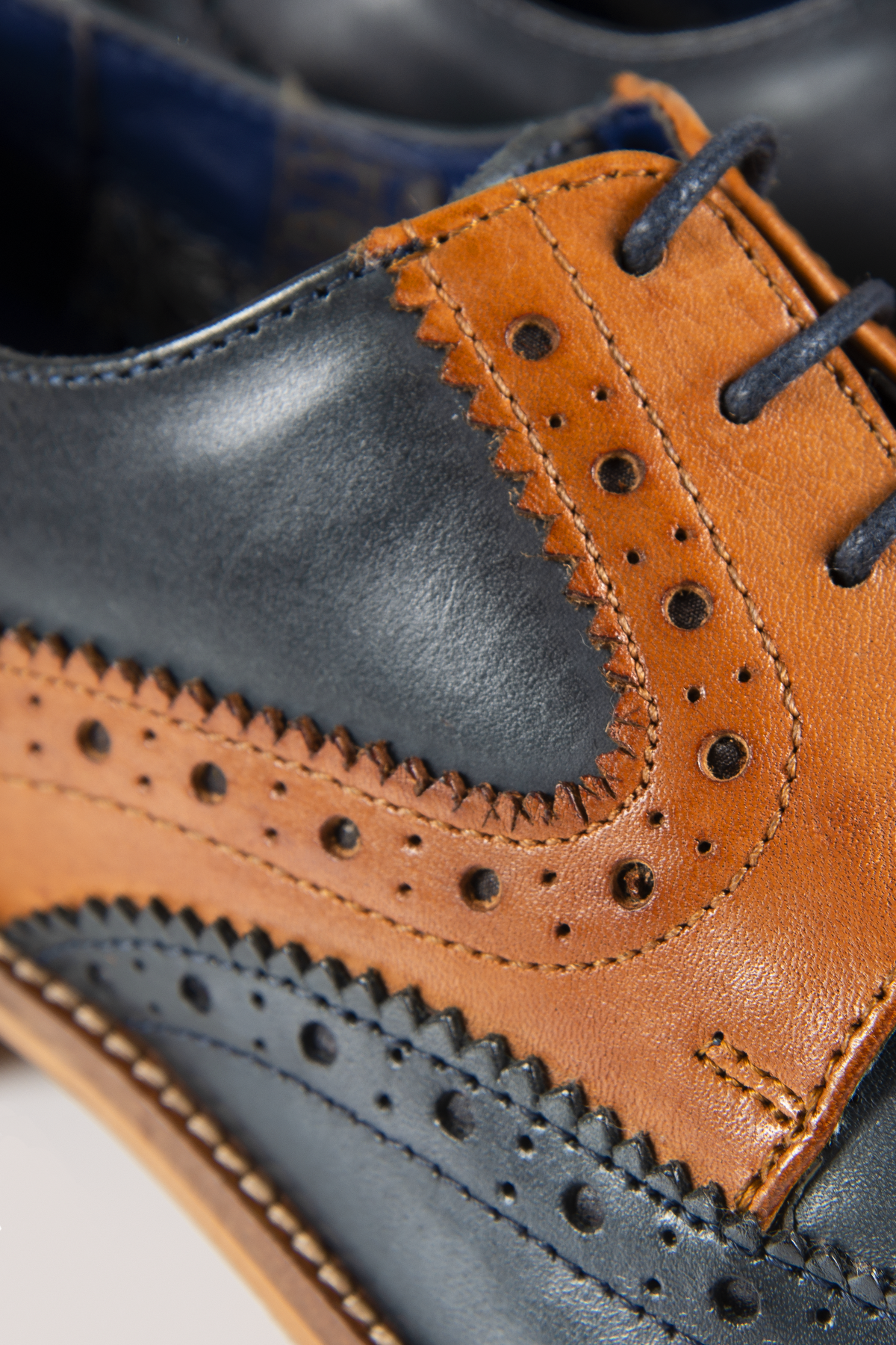 Close-up of the Marc Darcy RILEY Oxford Brogue shoe, featuring detailed stitching and perforated patterns in navy and tan leather.