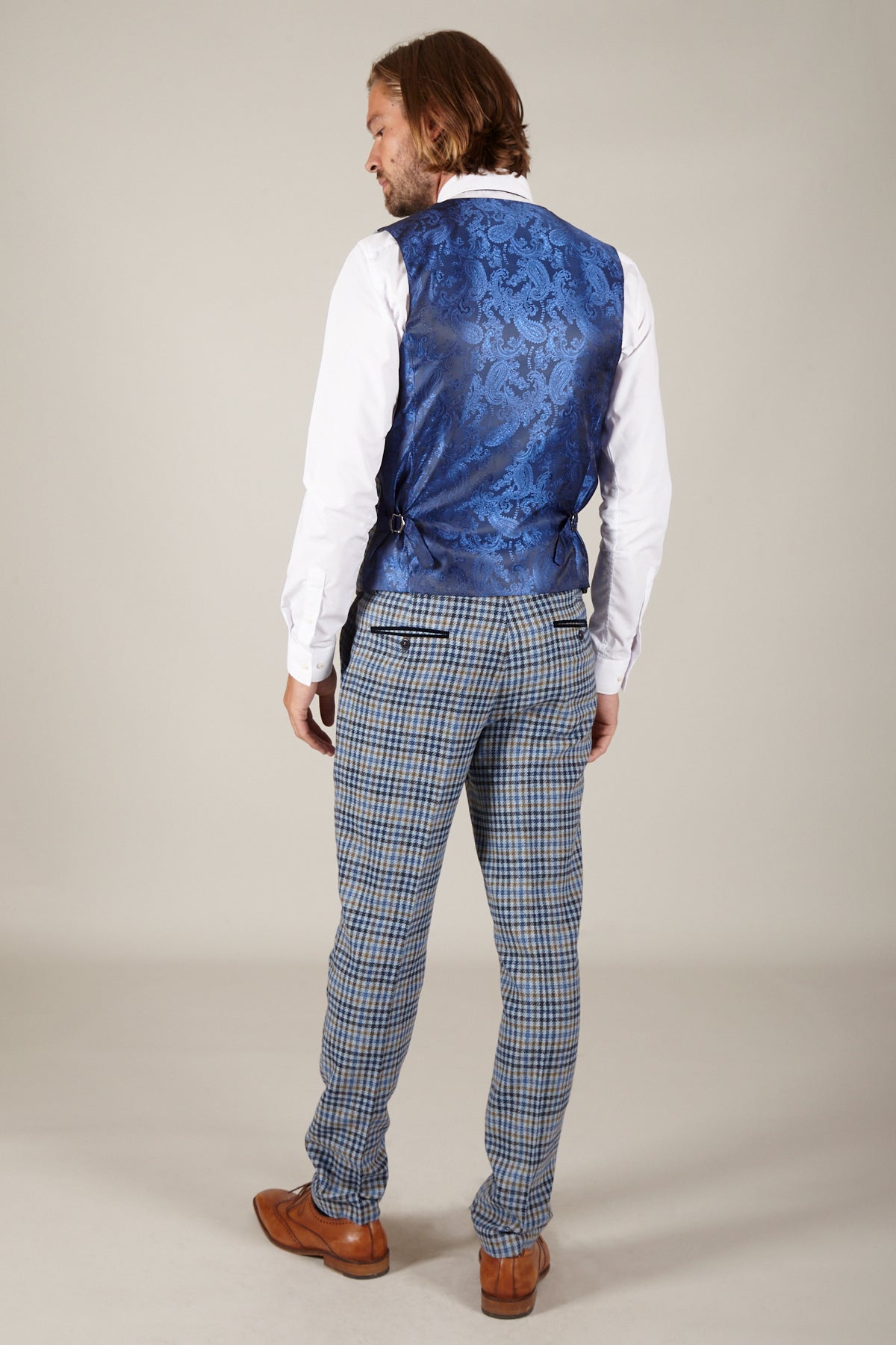 Rear view of a man in a white shirt, marcdarcy WATSON blue tan tweed check single-breasted waistcoat, blue plaid pants, and brown dress shoes.