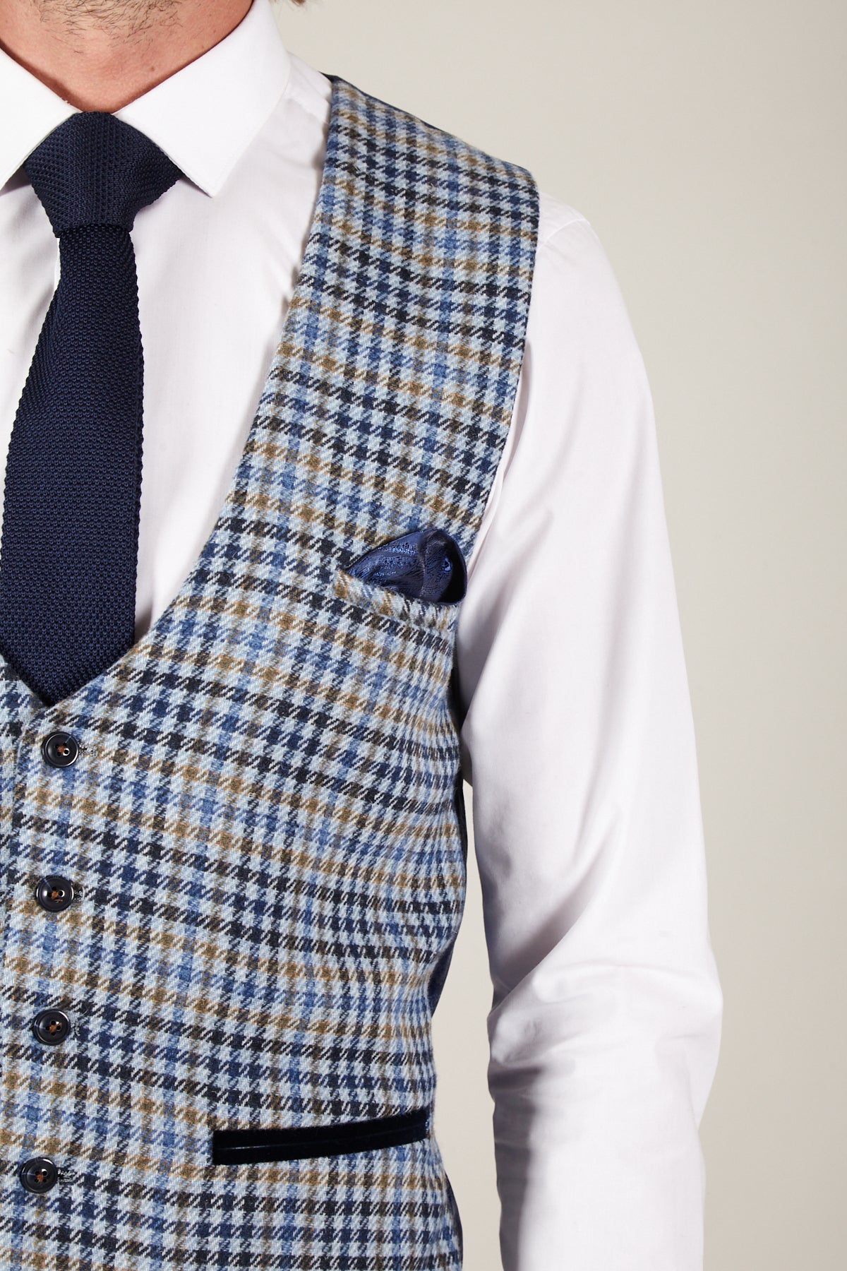 A person wears a white dress shirt, a navy knitted tie, the marcdarcy WATSON Blue Tan Tweed Check Single Breasted Waistcoat, and a navy pocket square.