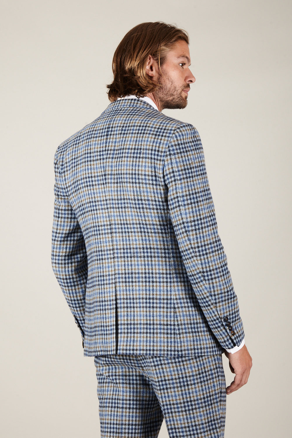 A man with medium-length hair is seen from behind wearing the Marc Darcy WATSON Blue Tan Tweed Check Blazer with matching pants and a white dress shirt, set against a plain light background.