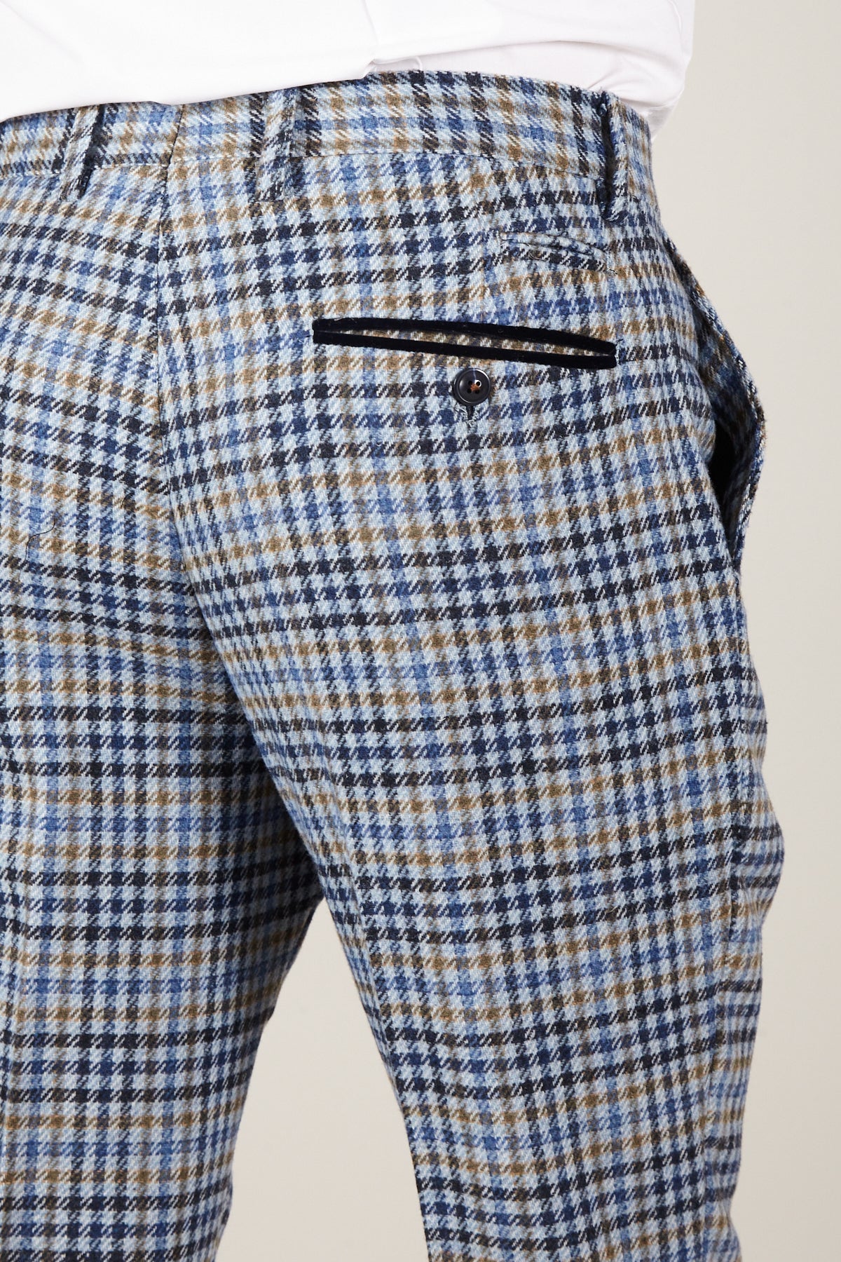 Close-up of a person wearing marcdarcy WATSON - Blue Tan Tweed Check Trousers, featuring a slim fit, blue and tan plaid, and a black buttoned back pocket against a plain light background.