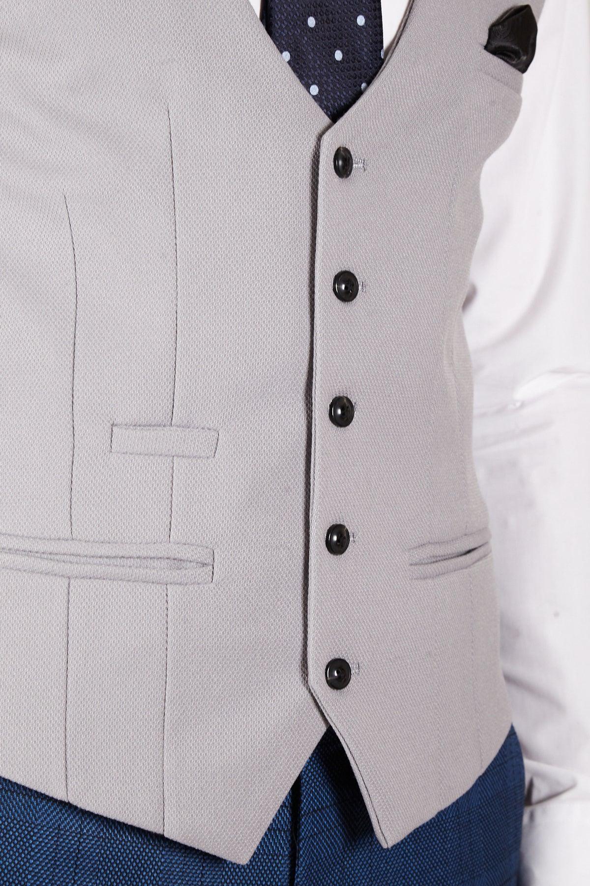 A close-up of a person wearing the marcdarcy KELVIN Silver Single Breasted Waistcoat with black buttons over a white shirt, blue trousers, a black pocket square, and a navy polka dot tie.