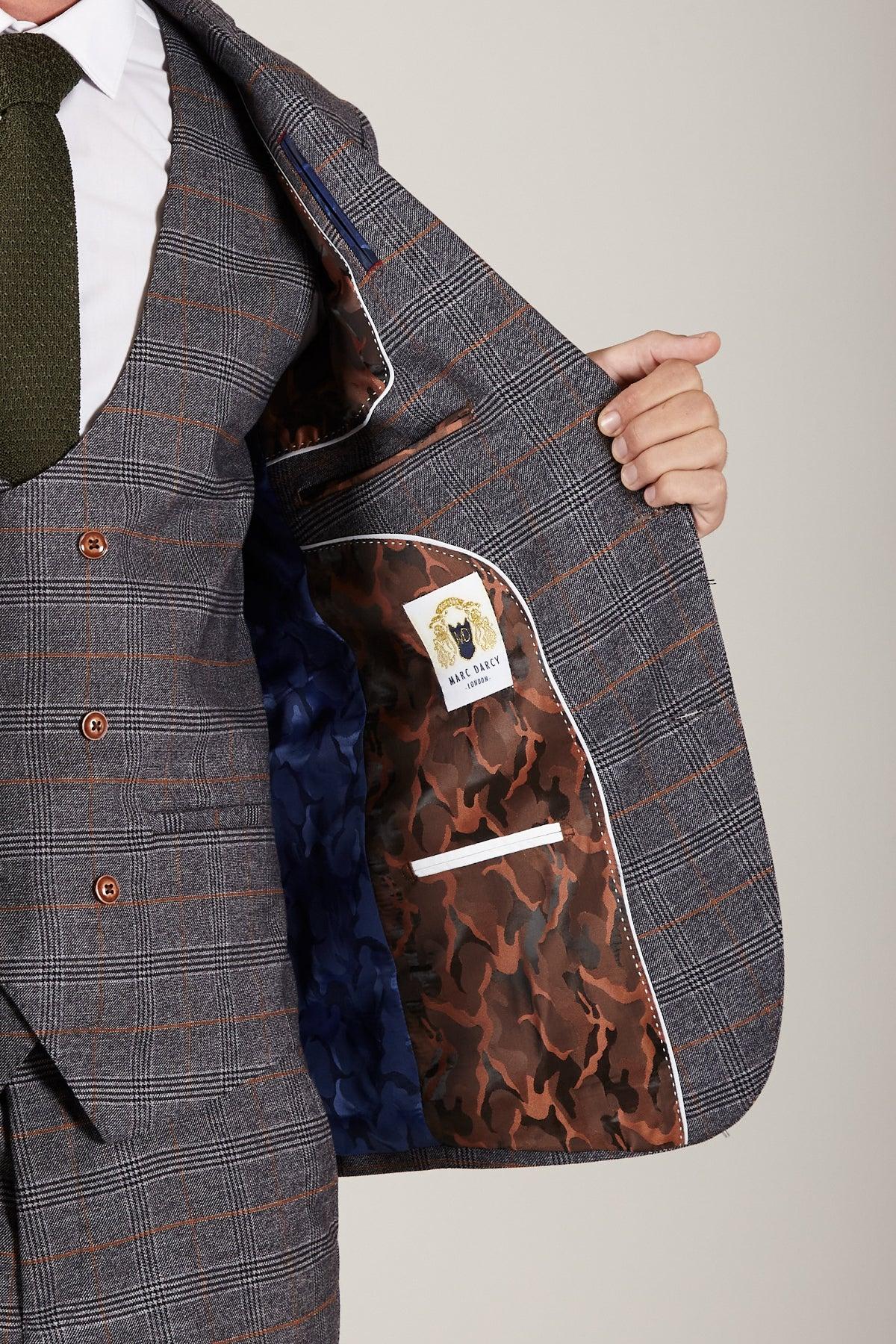 In The Everton Collection, Dominic Calvert-Lewin wears the marcdarcy JENSON Grey Suit, holding open the jacket to reveal a blue and brown camo lining with white trim and a lion label reading OUT RAGE.